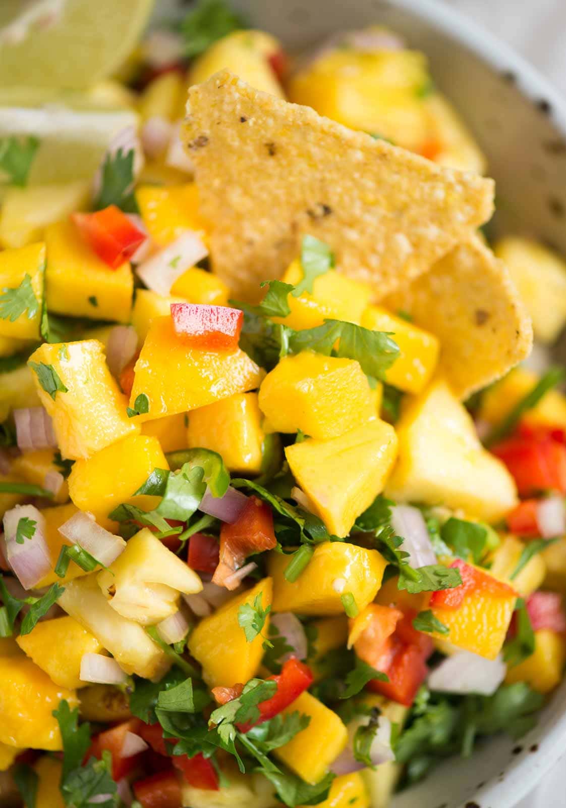 Close up image of pineapple mango salsa with chips in them.