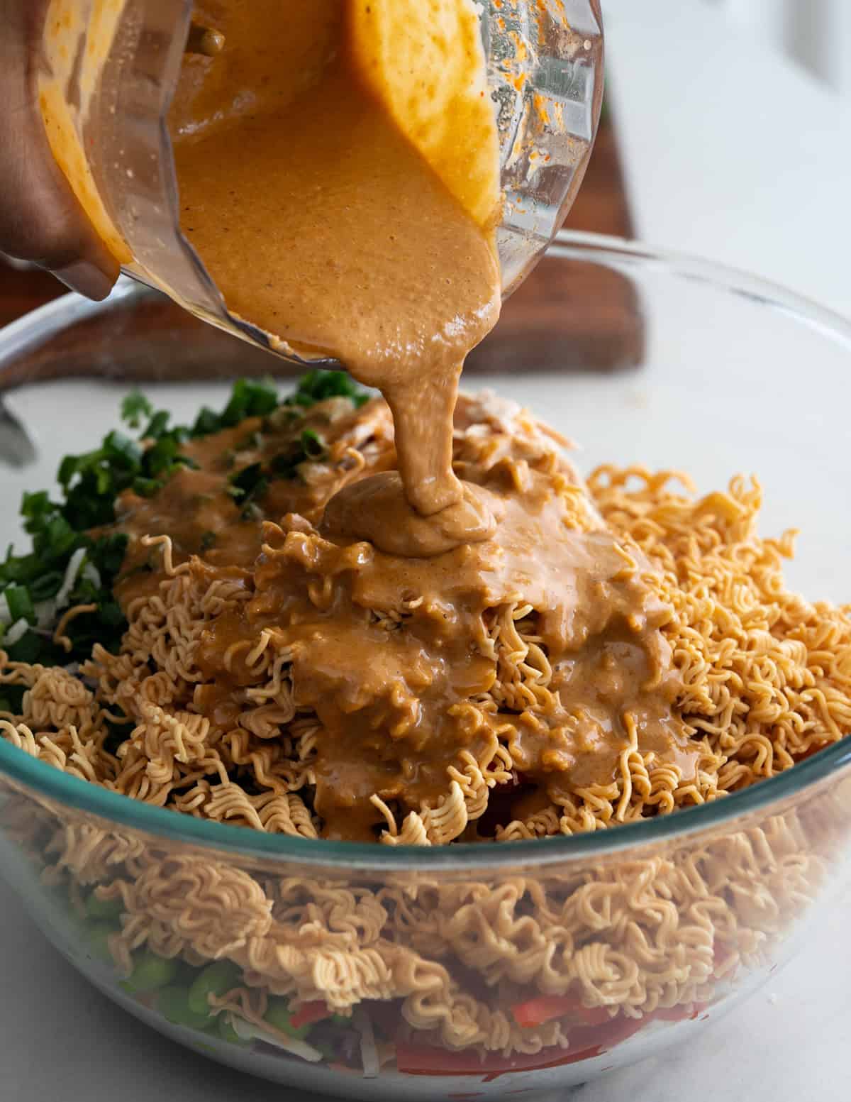 Pouring creamy peanut butter dressing on the salad.