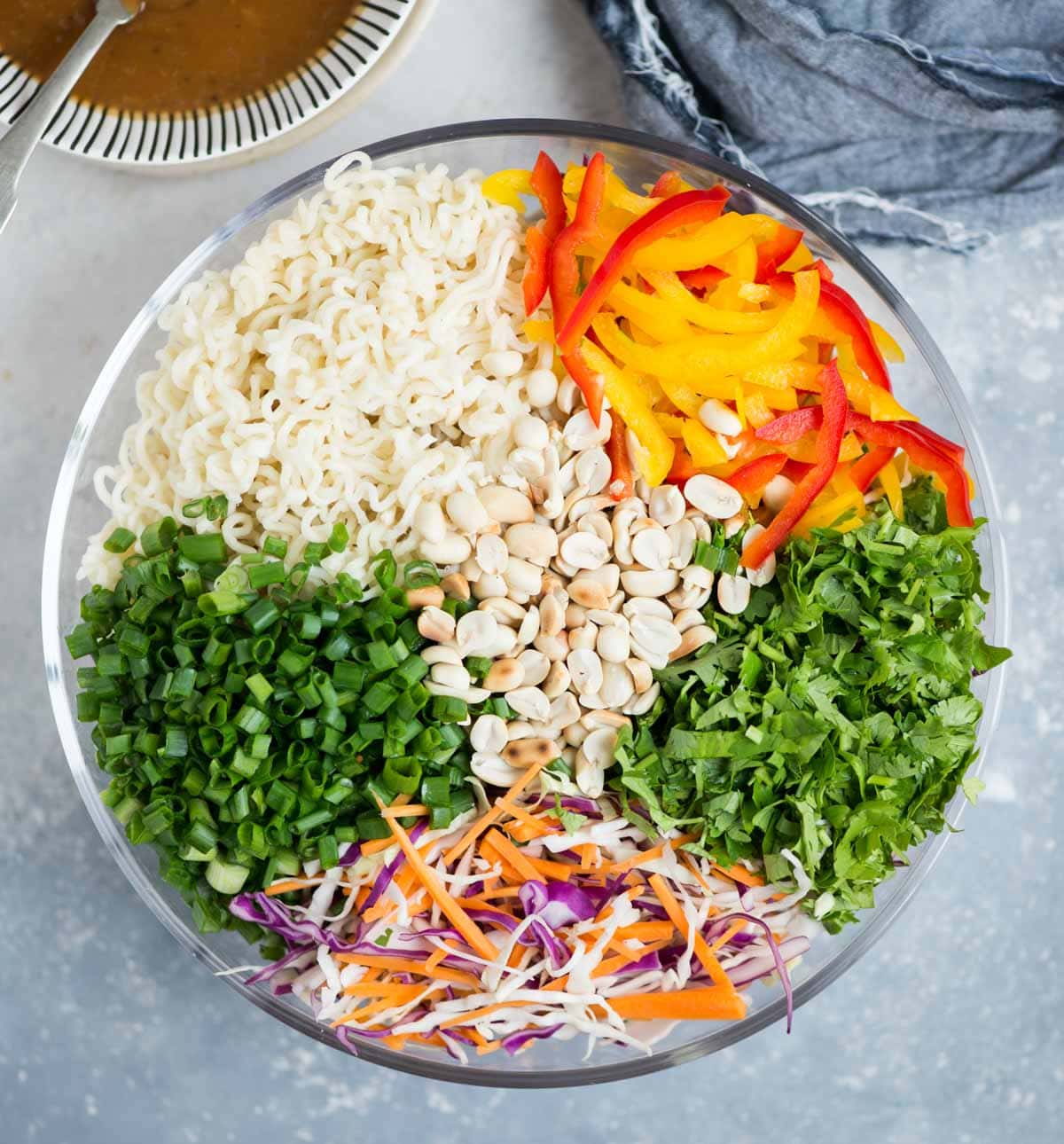Ingredients for making Ramen Noodle Salad - Ramen noodle, coleslaw mix, bell pepper, green onion, roasted peanuts and asian peanut butter dressing.