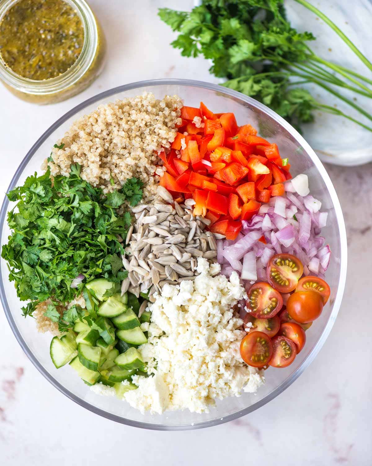 Ingredients required to make quinoa salad - quinoa, cherry tomato, herbs, cucumber, sunflower seeds, onion.