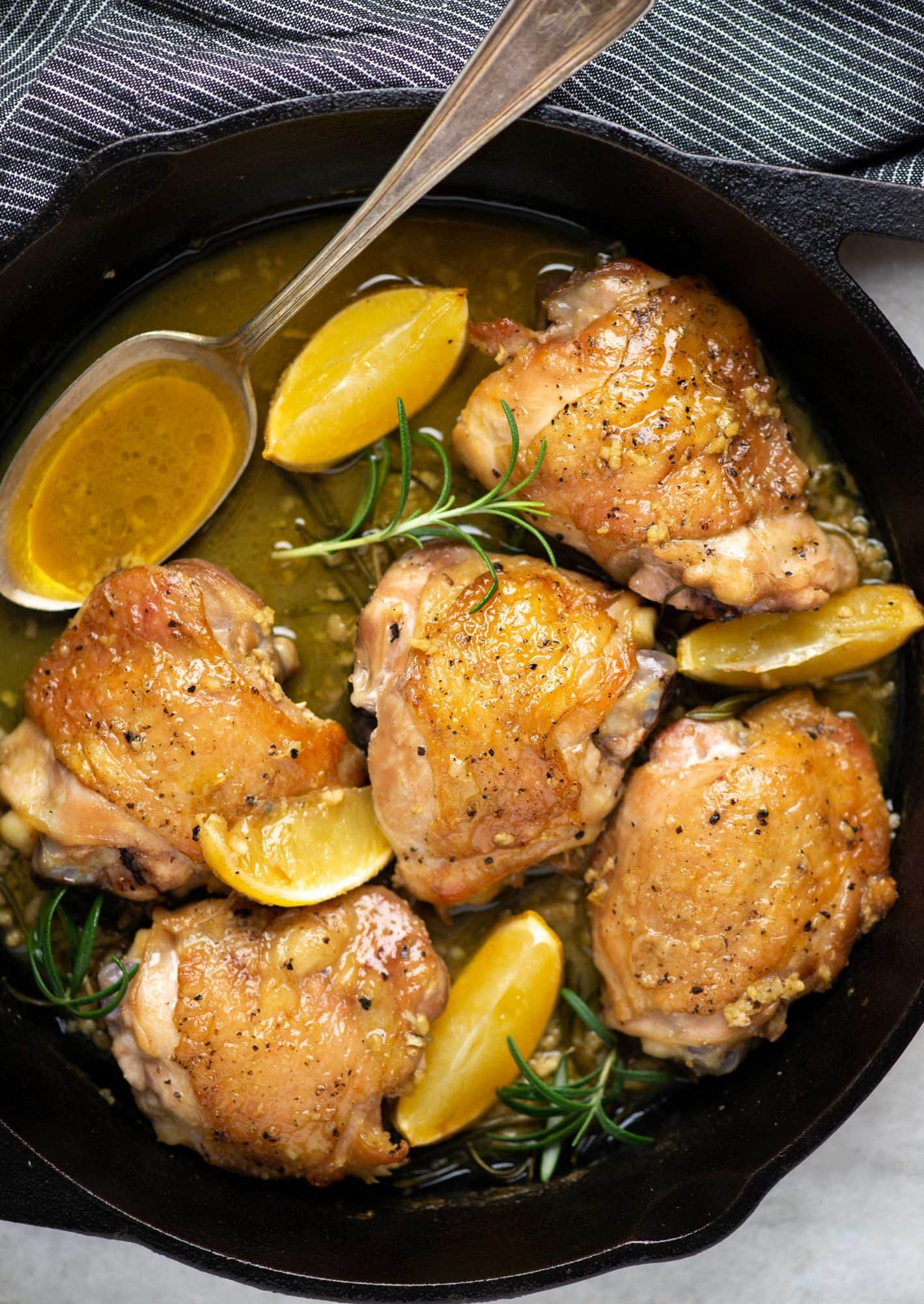 Rosemary infused lemon garlic butter sauce around baked chicken thighs with crispy skin made in a skillet and finished in the oven. 