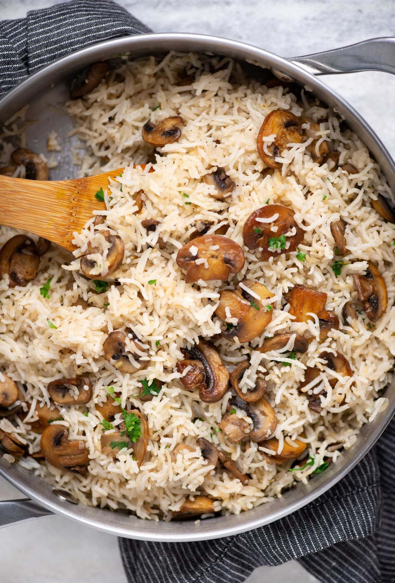 Mushroom rice made as a one-pot dish shown in a pot with brown colored rice and sauteed mushrooms.