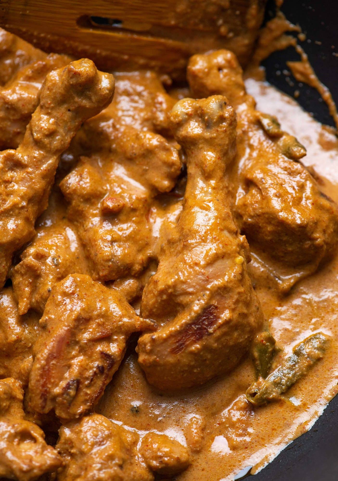 Close up picture of rich and creamy chicken korma being cooked in a kadhai/skillet.