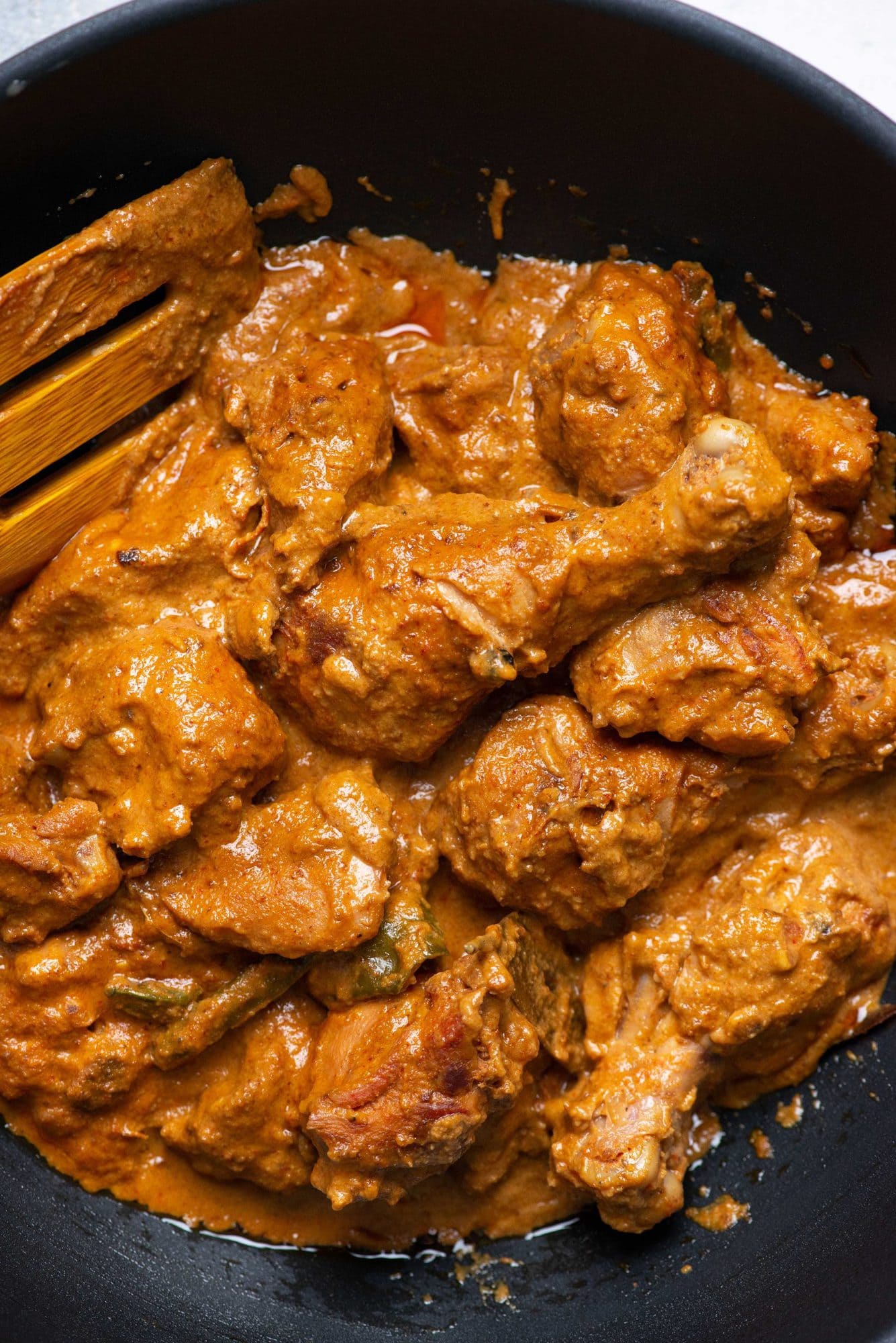 Rich and creamy Indian chicken korma curry being cooked in a skillet/kadhai.