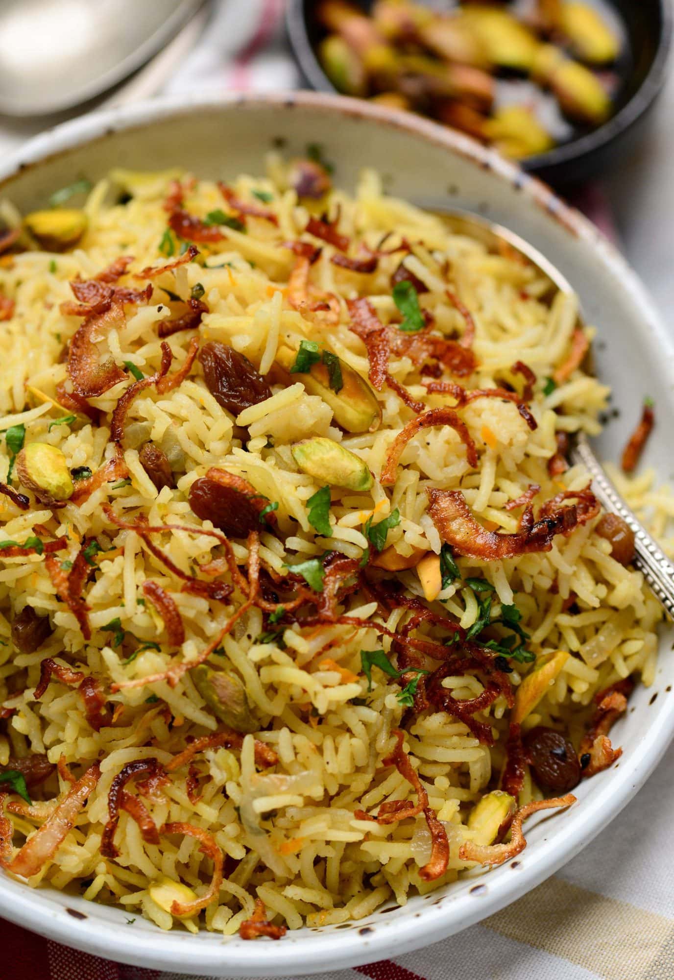 Close-up shot of a bowl of rice pilaf made with dry fruits, spices and nuts and caremelized onions on top.