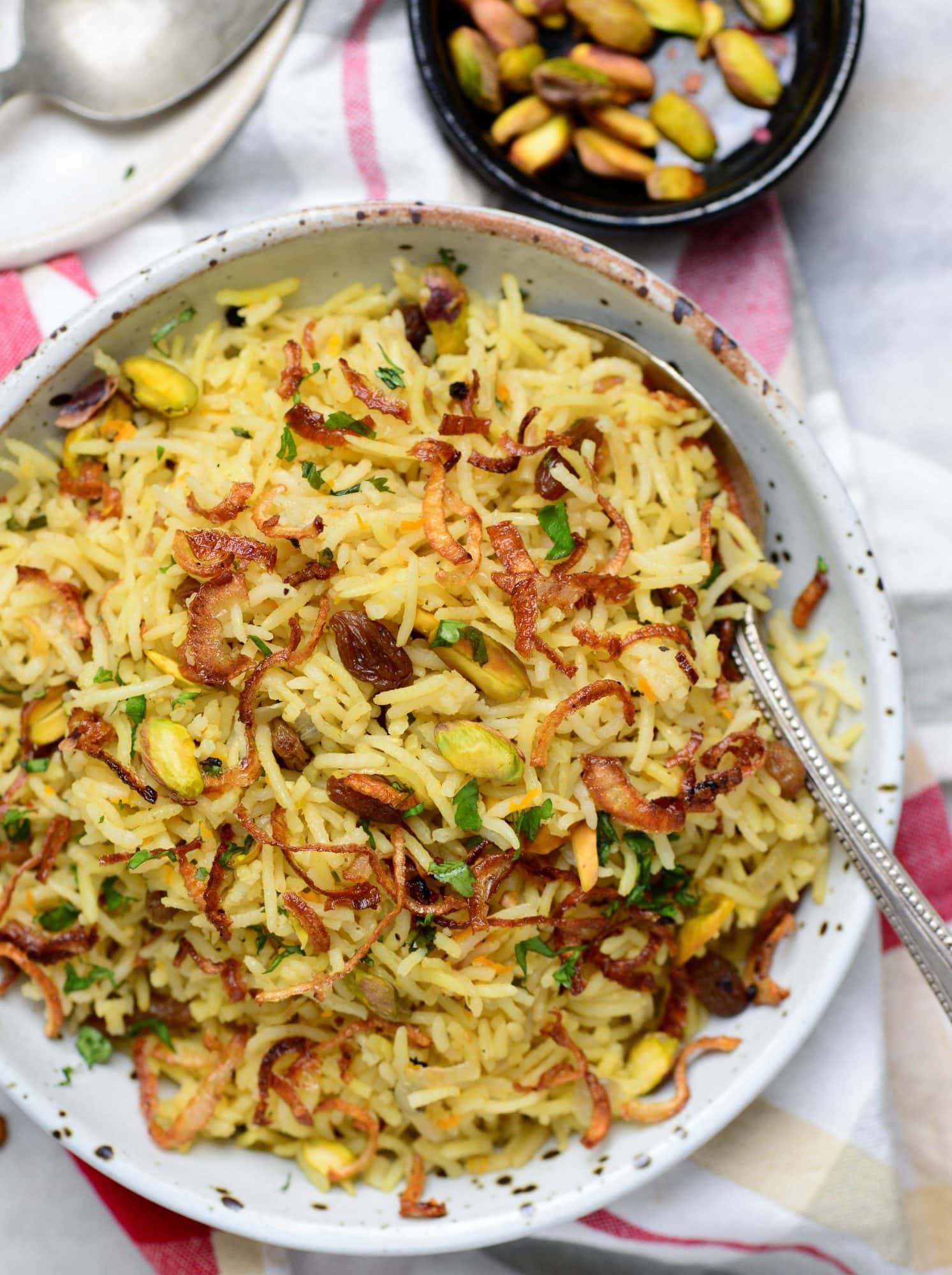 Bowl of rice pilaf made with dry fruits, spices and nuts and caramelized onions on top.