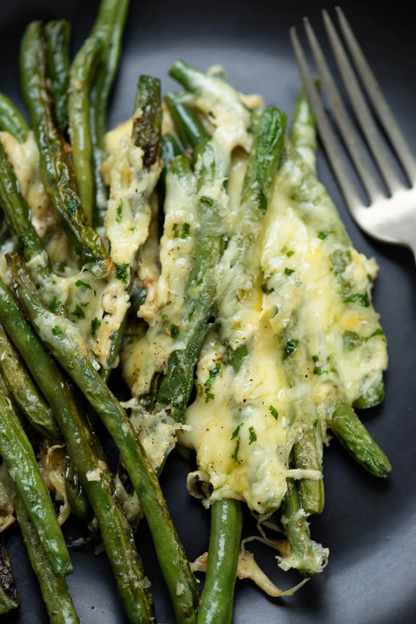 Image of cheese garlic roasted green beans served on a plate with a fork.