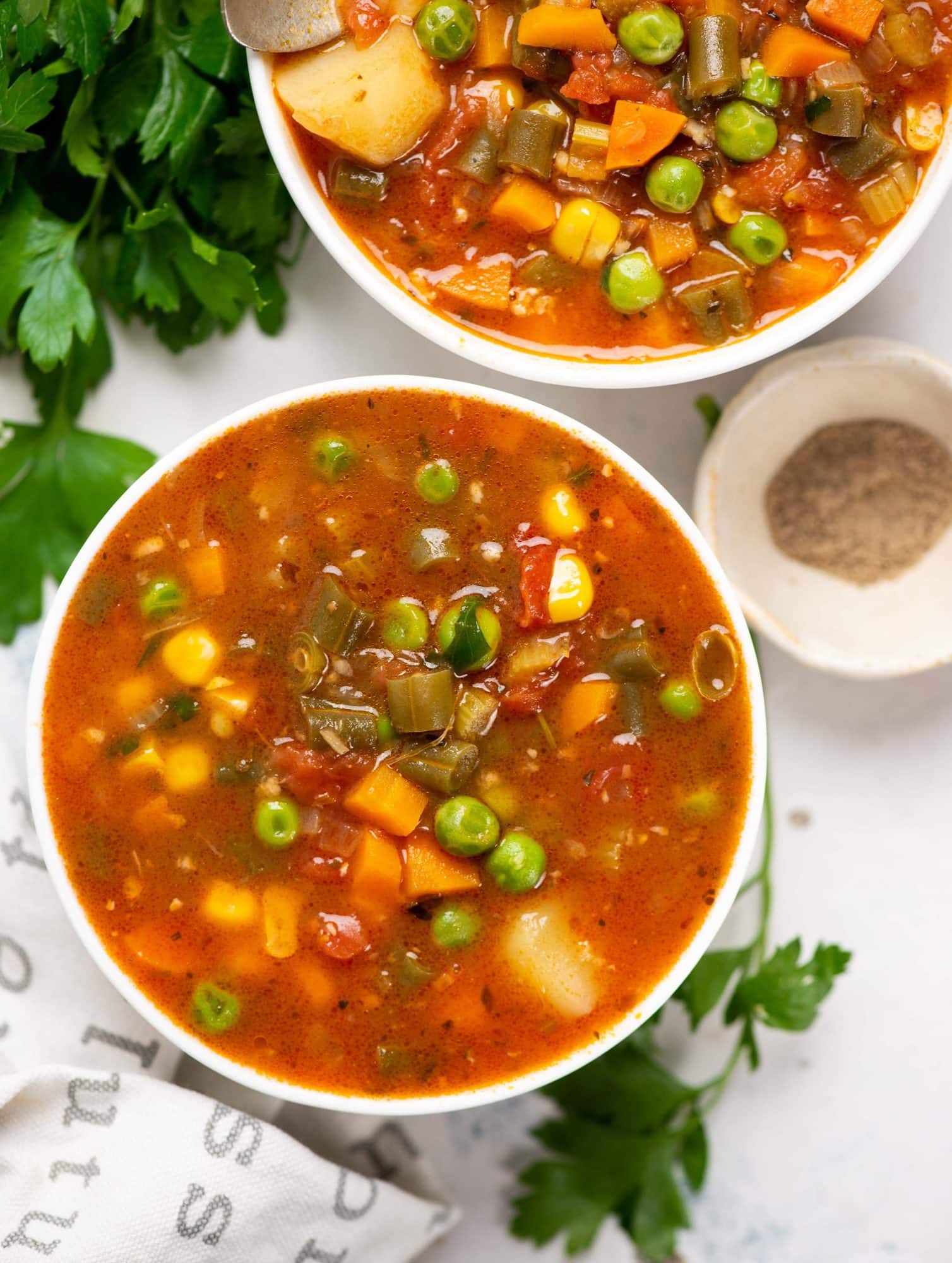 Vegetable soup made of potatoes, carrots, peas and beans served in 
two white bowl.