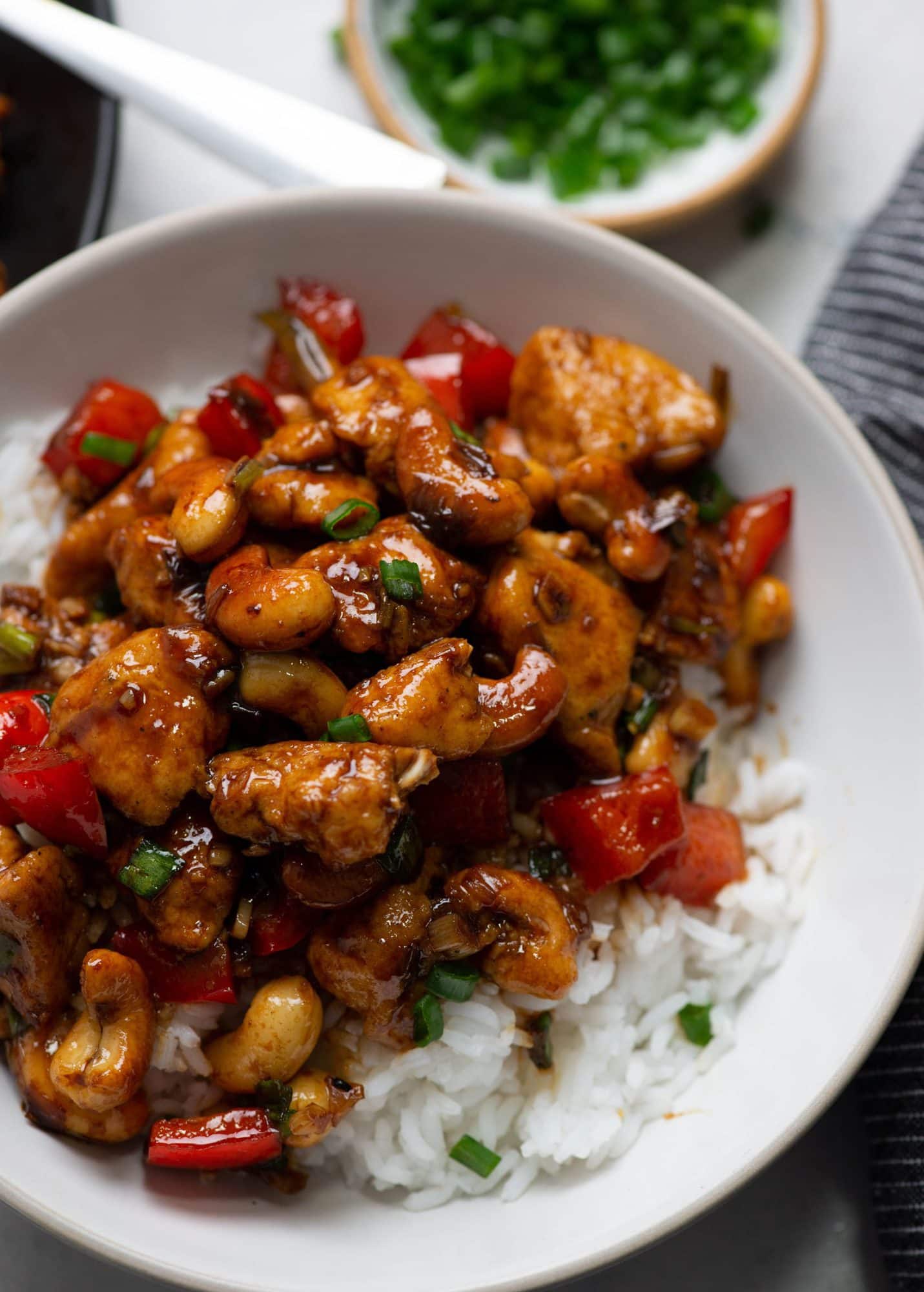 Chicken Stir Fry with thai flavors served on a bed or rice in a white bowl