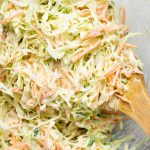 Close up view of creamy cabbage coleslaw with a wooden ladle in it