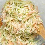 Creamy coleslaw made in a bowl shown with a wooden ladle