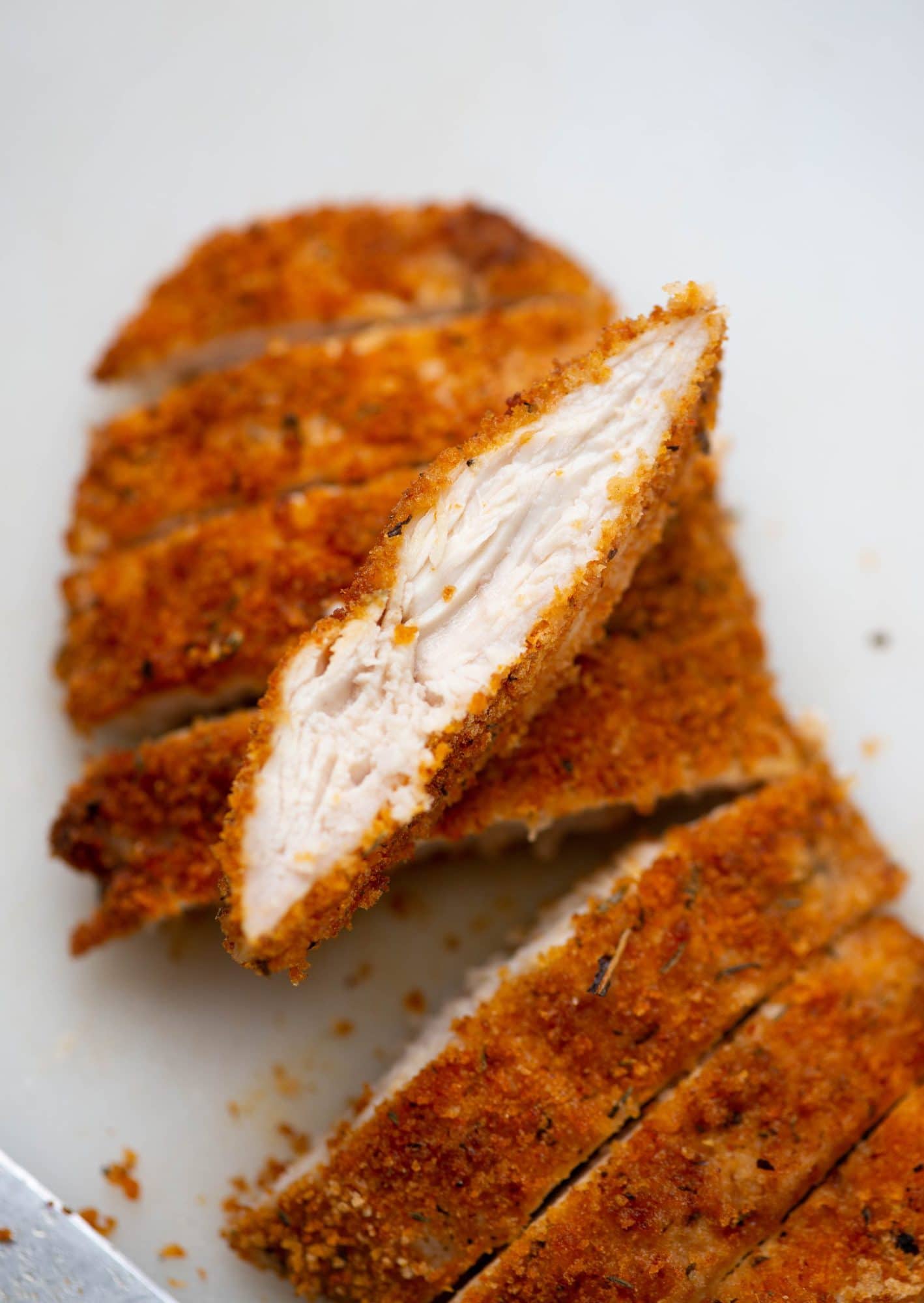 Slice of Air fried chicken breast shows crispy crust on outside and juicy chicken inside.