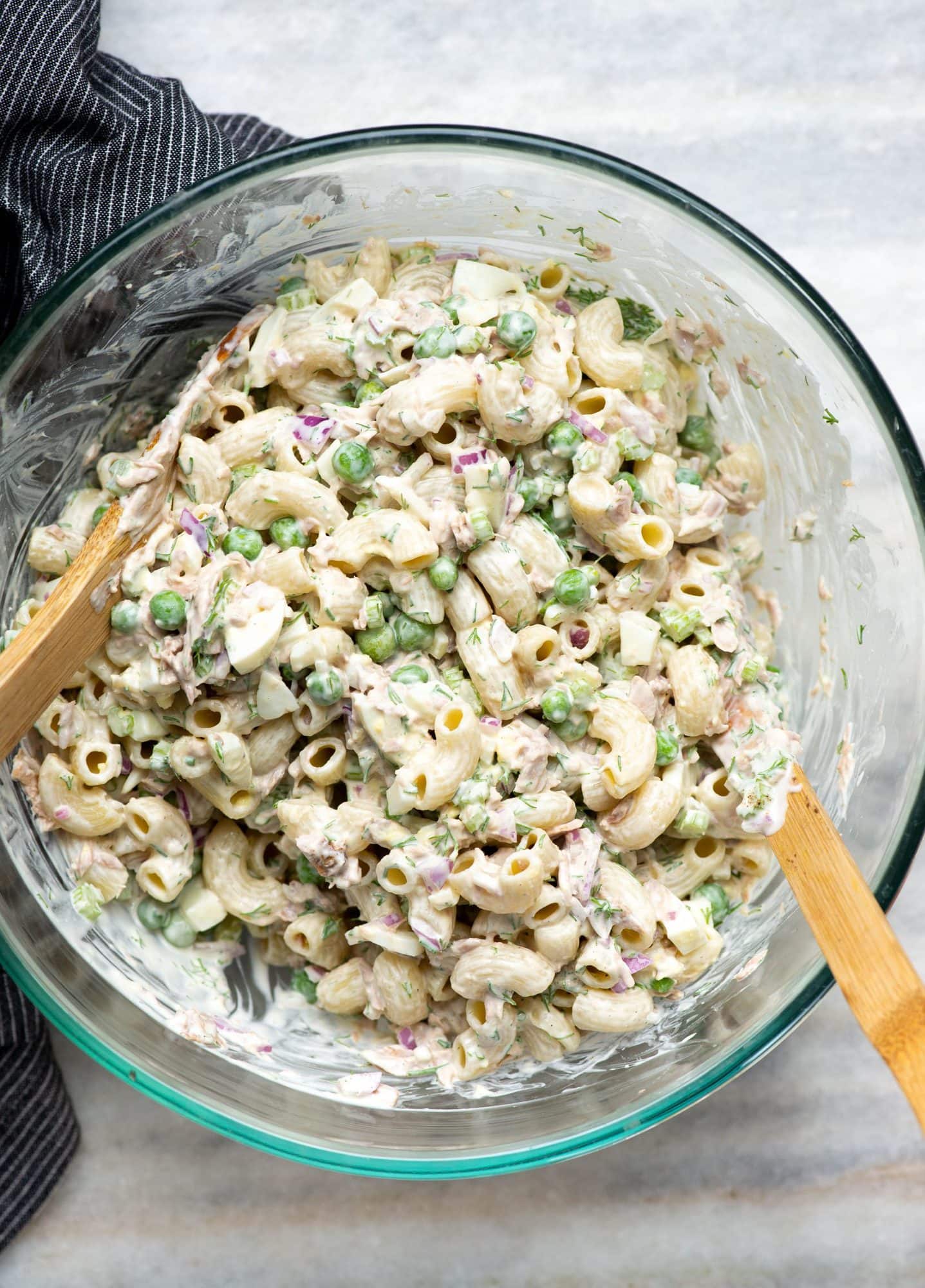 A bowl of tuna pasta salad done with a creamy dressing with two wooden spoons.