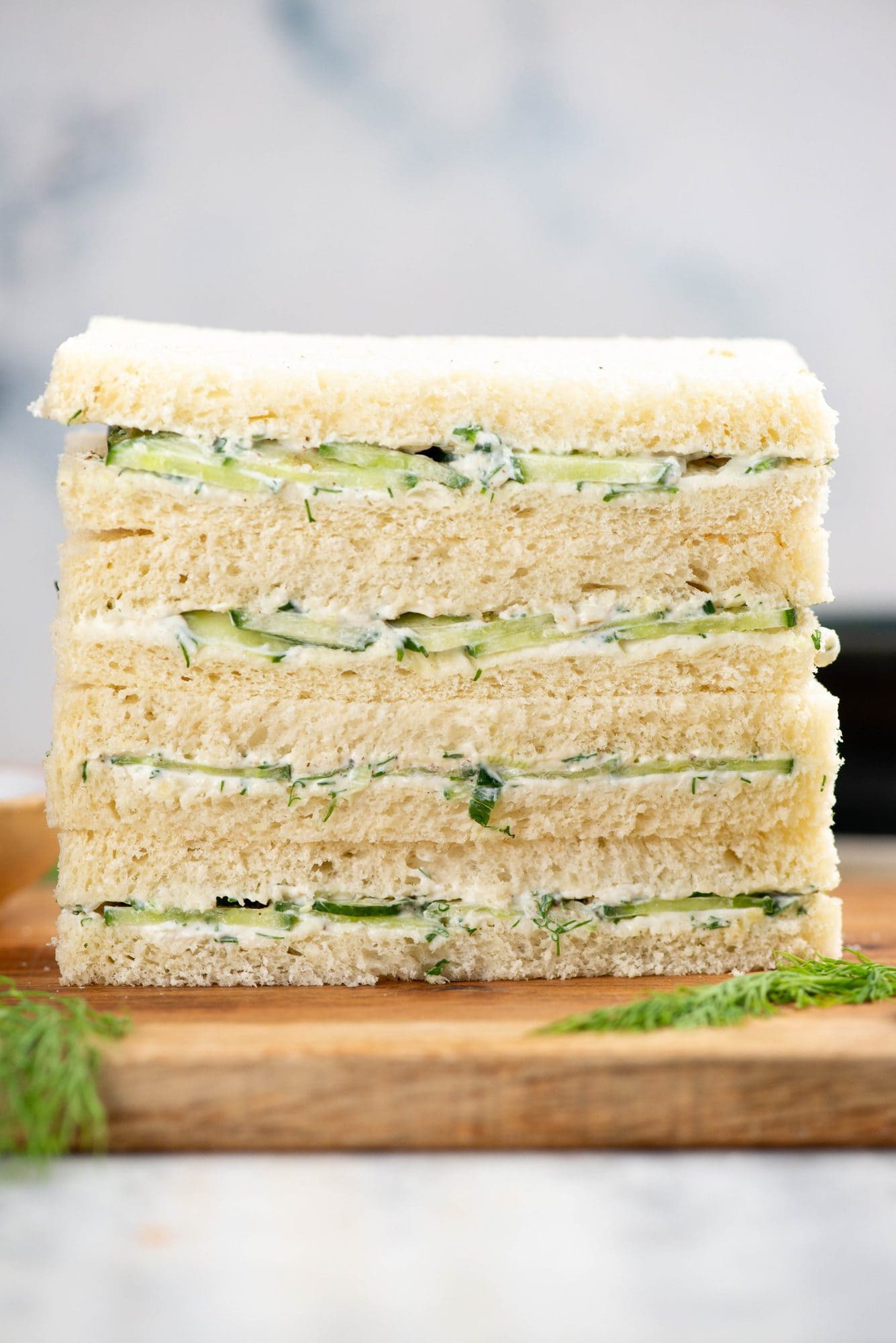 Stack of cucumber sandwiches with a creamy flavorful spread and sliced cucumber.