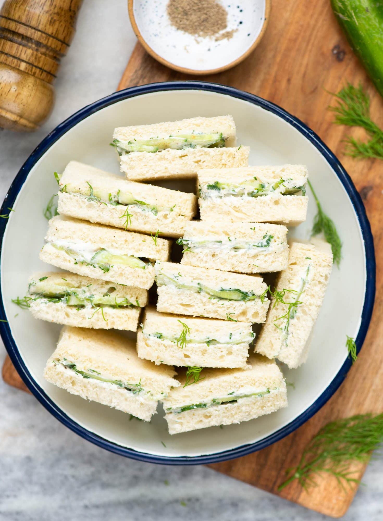 Cucumber sandwiches cut into halves and arranged in a big plate.