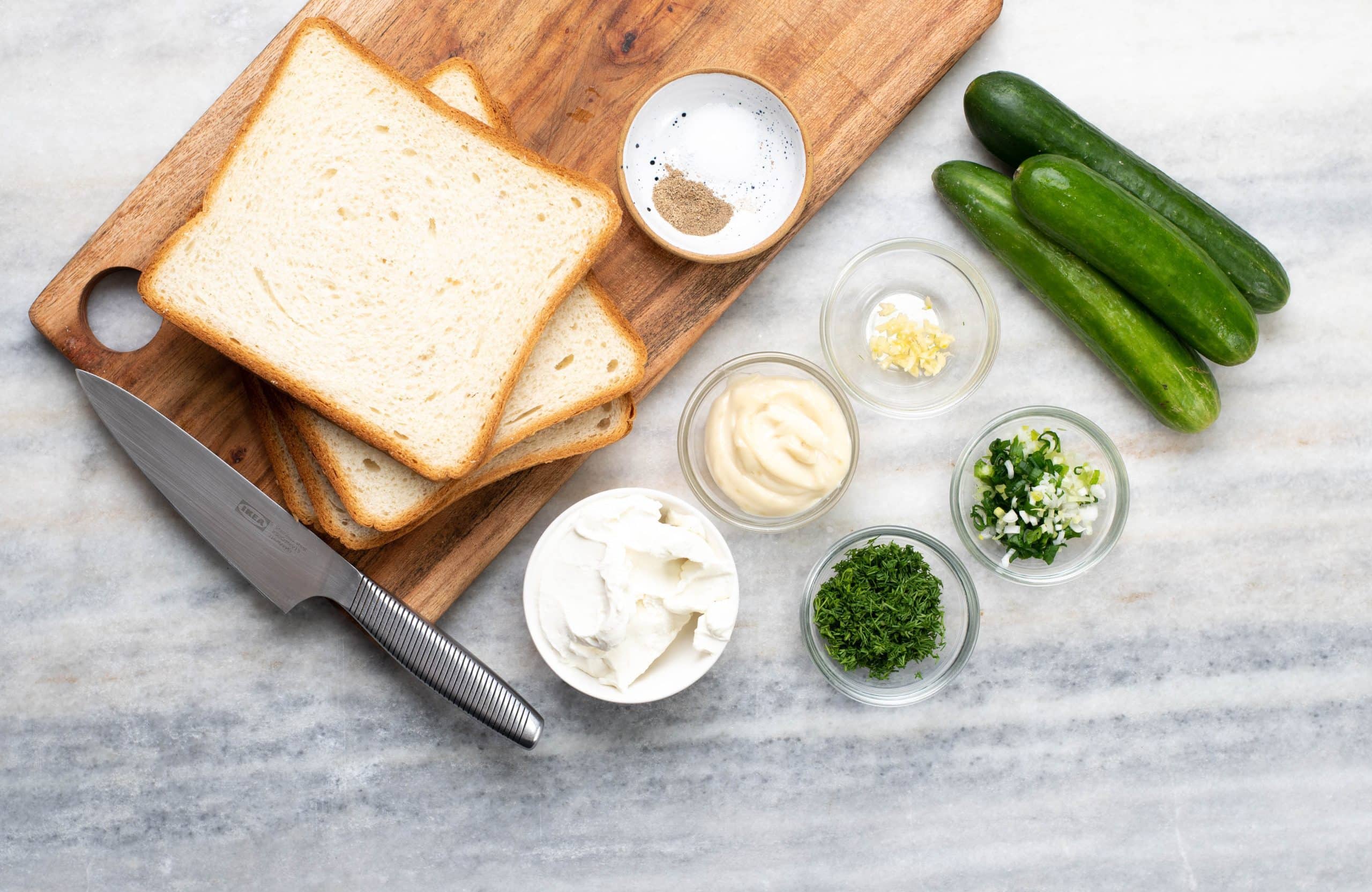 Ingredients to make Tea cucumber sandwiches - Bread slices, cucumbers, cream, cheese, herbs and spices to make the spread.