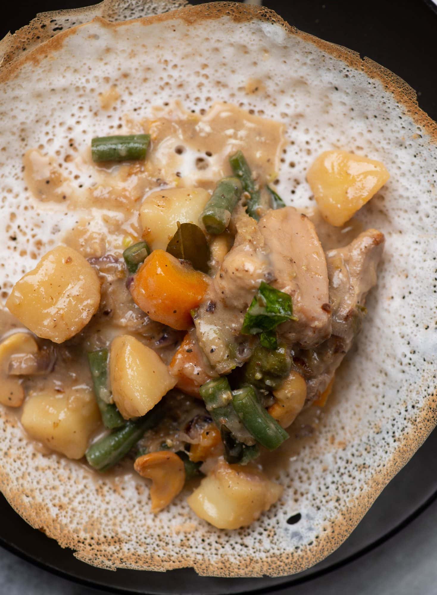 Chicken stew made kerala-style is served on a Appam (a kerala bread made of rice)