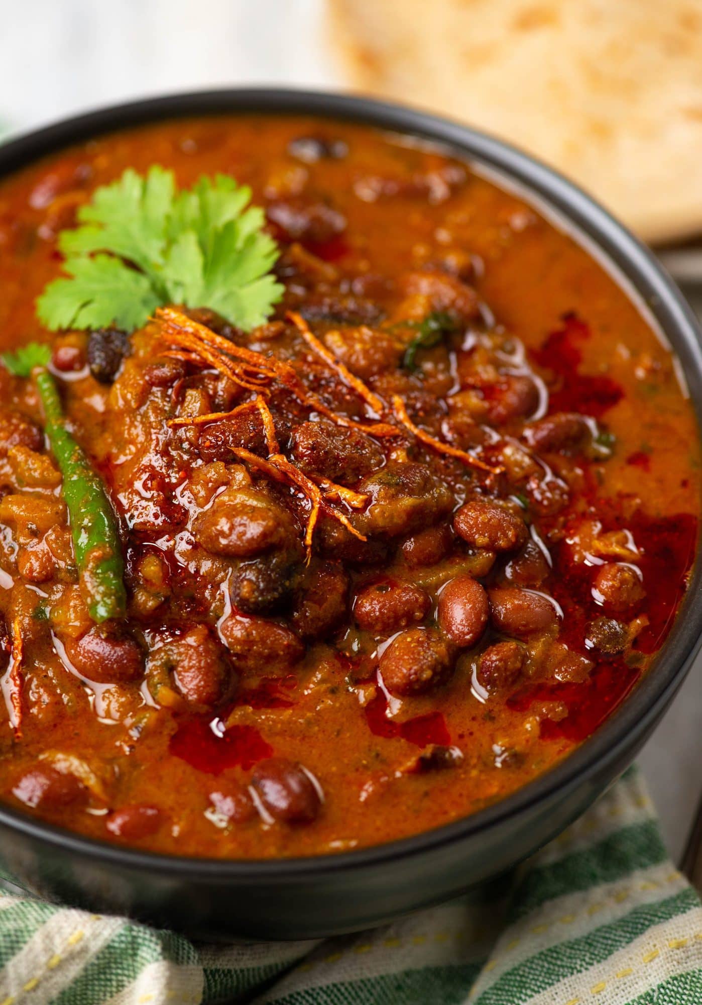 Rajma masala served on a bowl wti chilies, ginger juliennes and coriander leaves on top.