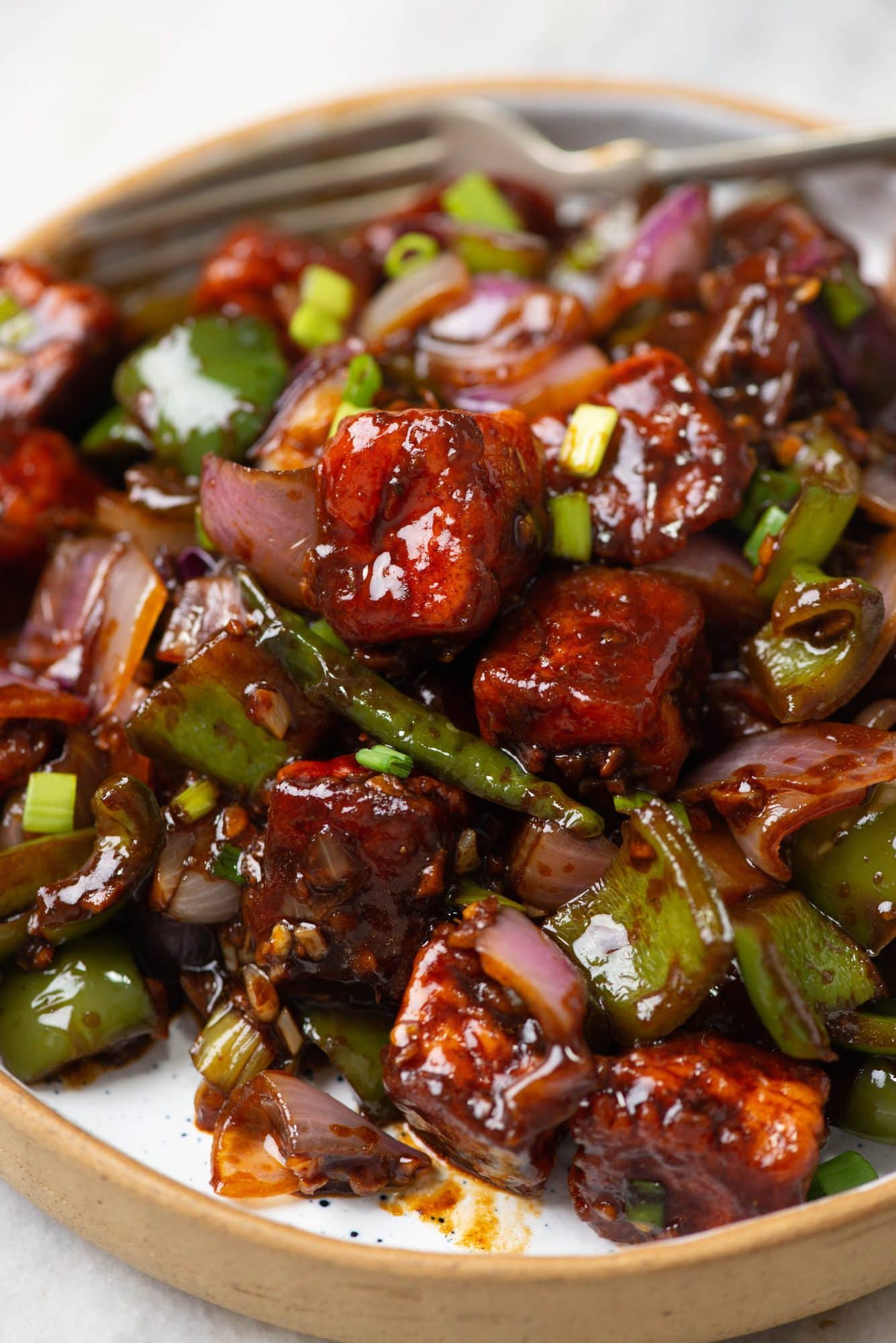 Paneer pieces coated in a batter, deep-fried until crispy, and then tossed along with ginger, garlic, onion and capsicum in an Indo-Chinese savory sauce. 