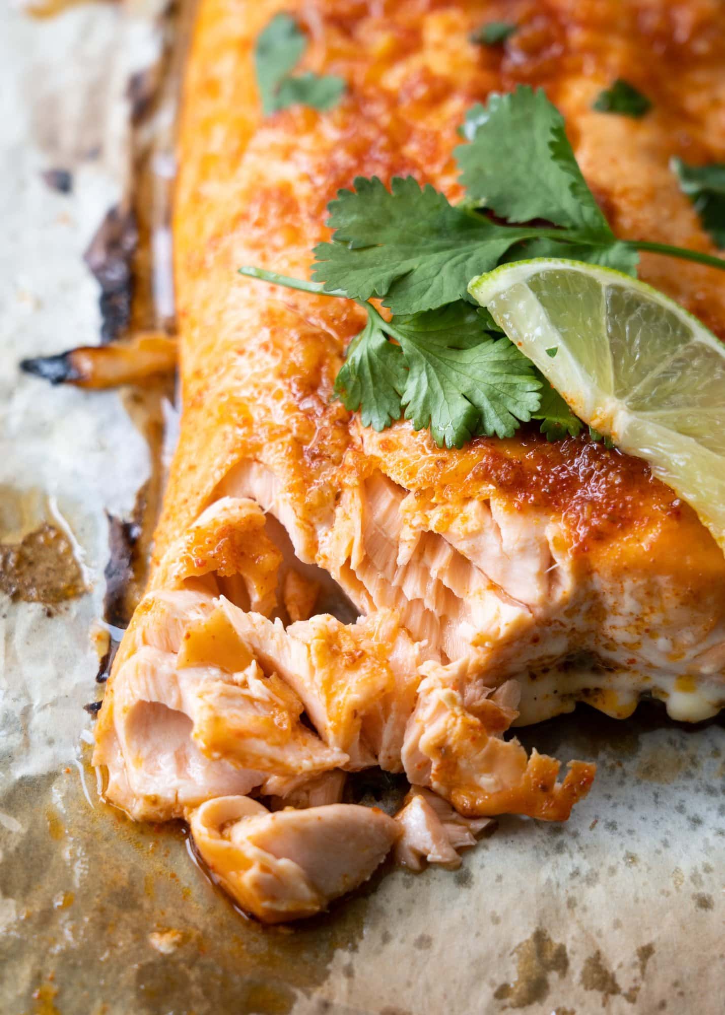 Baked salmon has tender and flaky meat inside as shown in the image with celery and a lime slice.