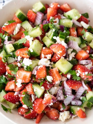 Strawberry cucumber salad with cheese and onions in a bowl