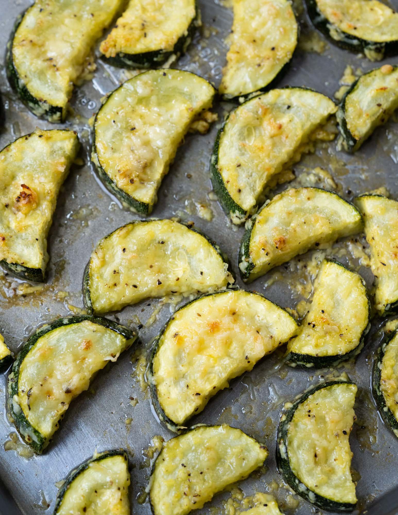 Parmesan coated roasted zucchini in oven on a tray.