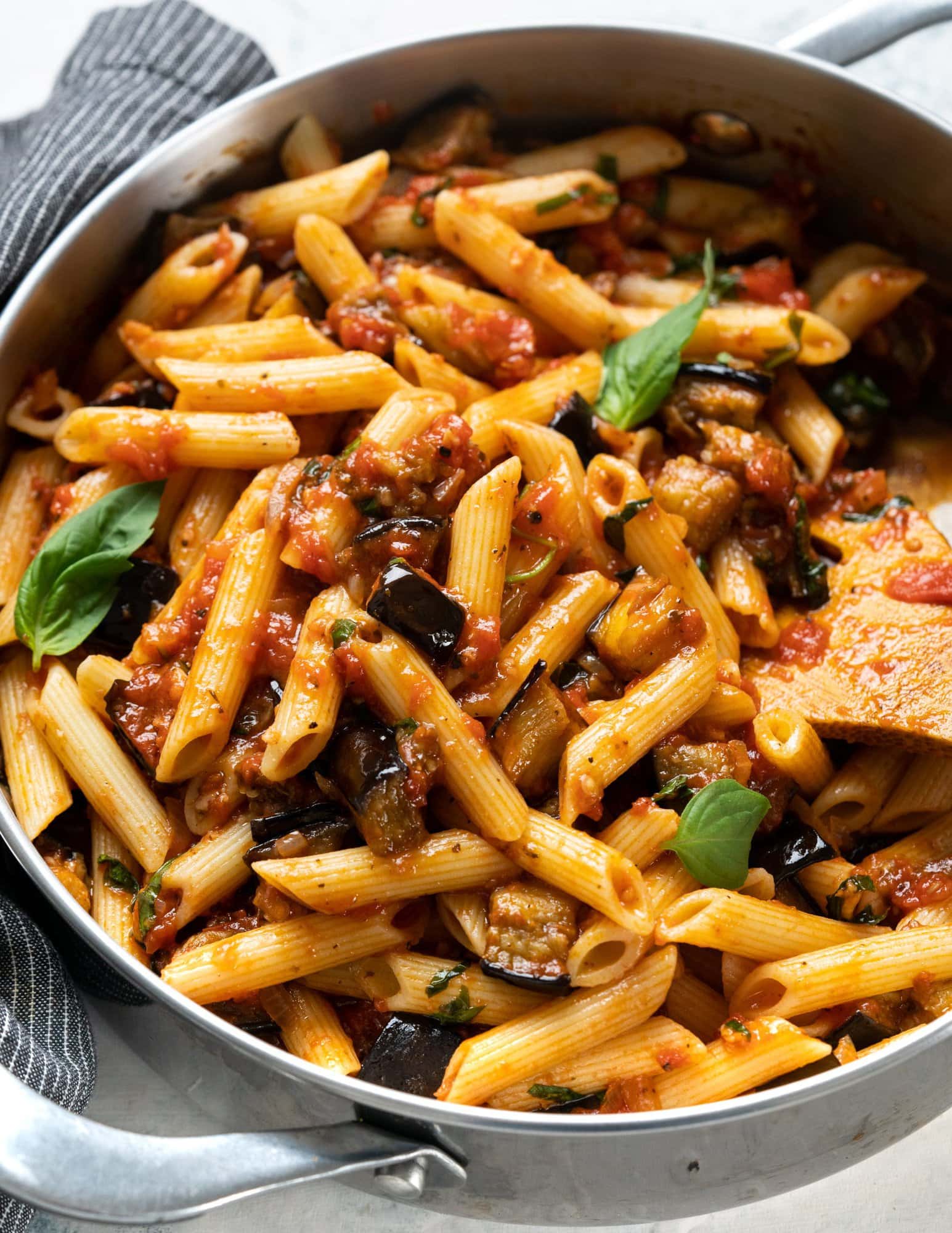 Pasta Alla Norma, made in a pan with penne pasta and baked eggplant on a tomato sauce, in a pan.