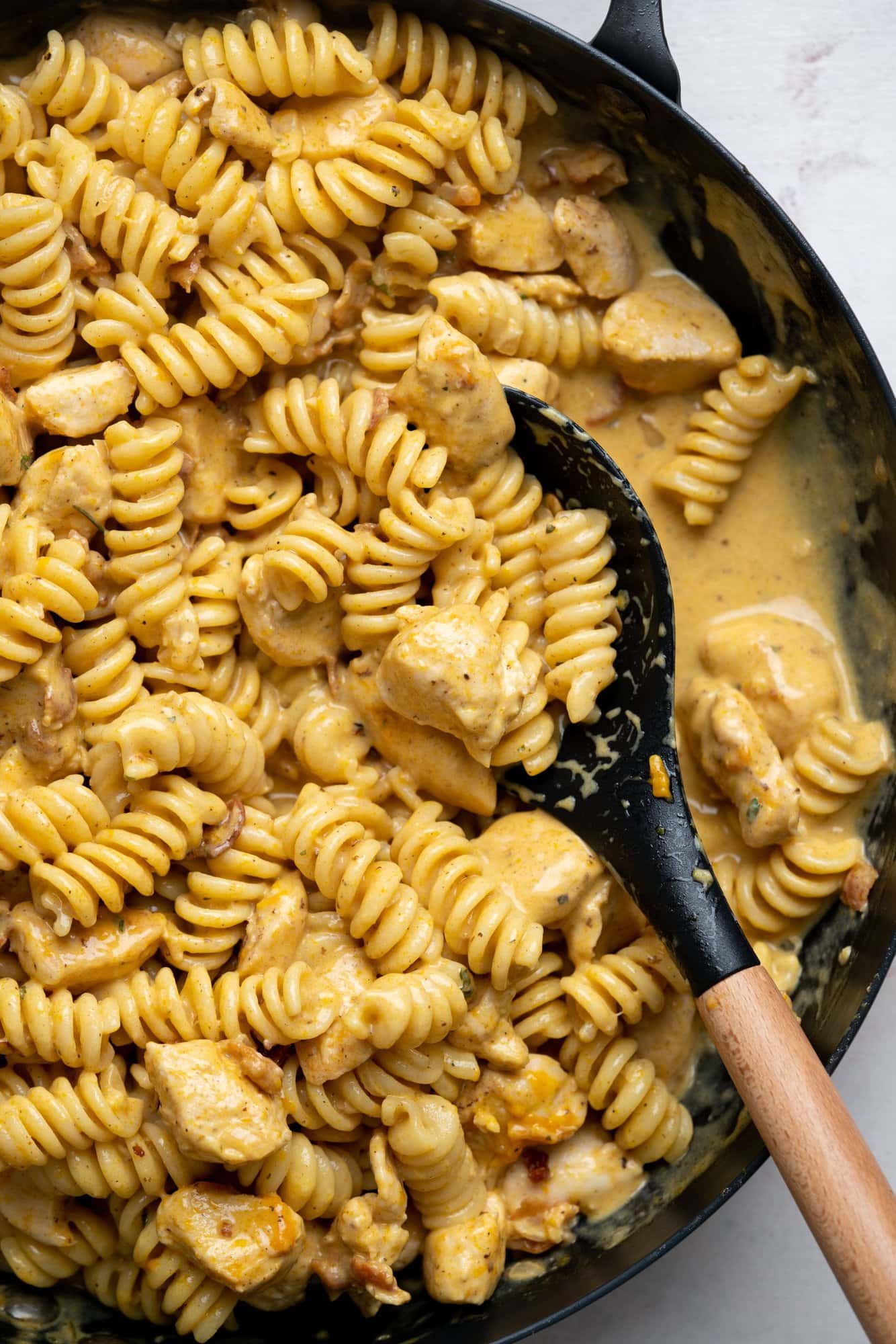 Chicken pasta made with a creamy cheesy sauce with ranch seasoning in a skillet.