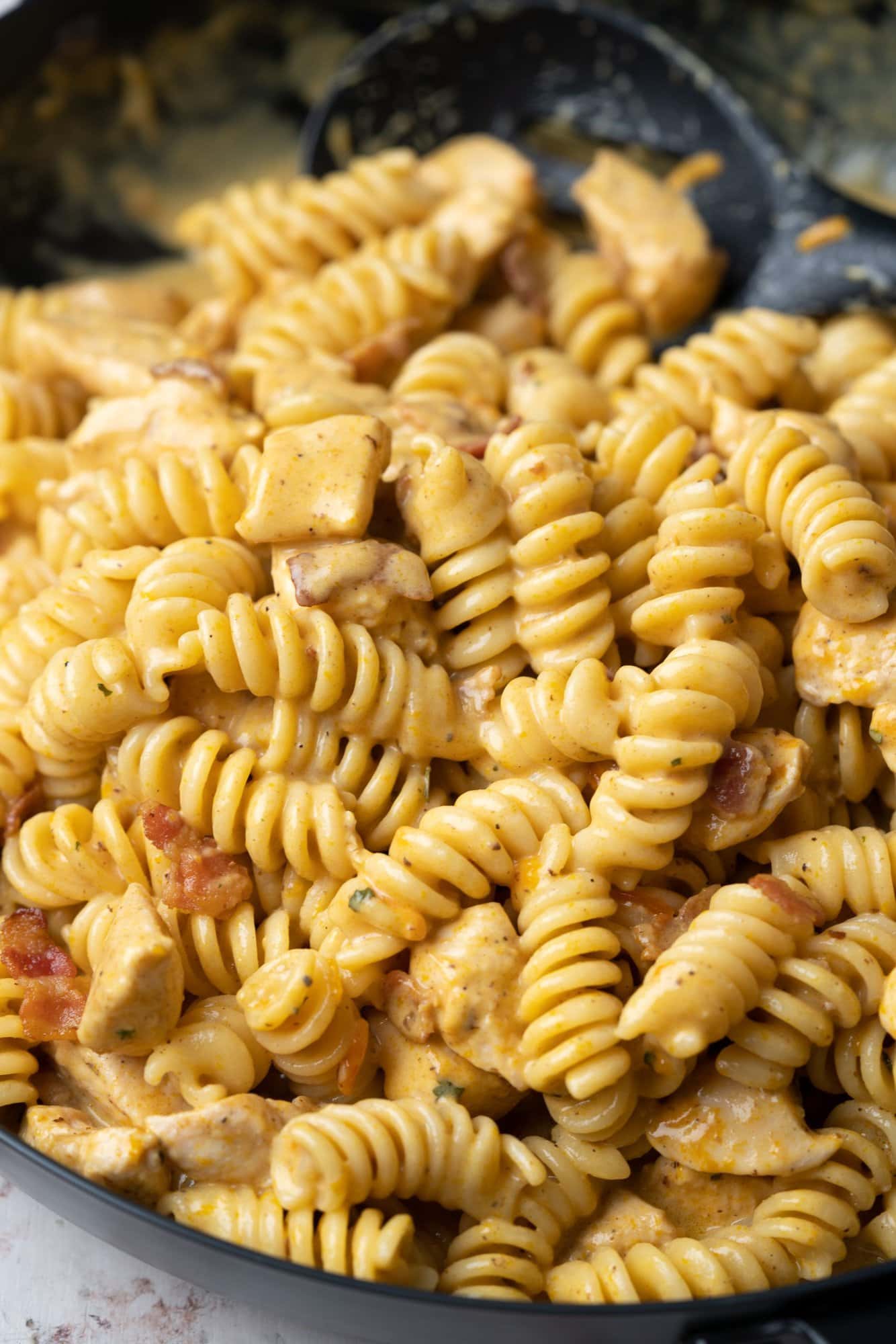 Close view of cheesy saucy chicken pasta made with flavors of ranch seasoning and bacon.