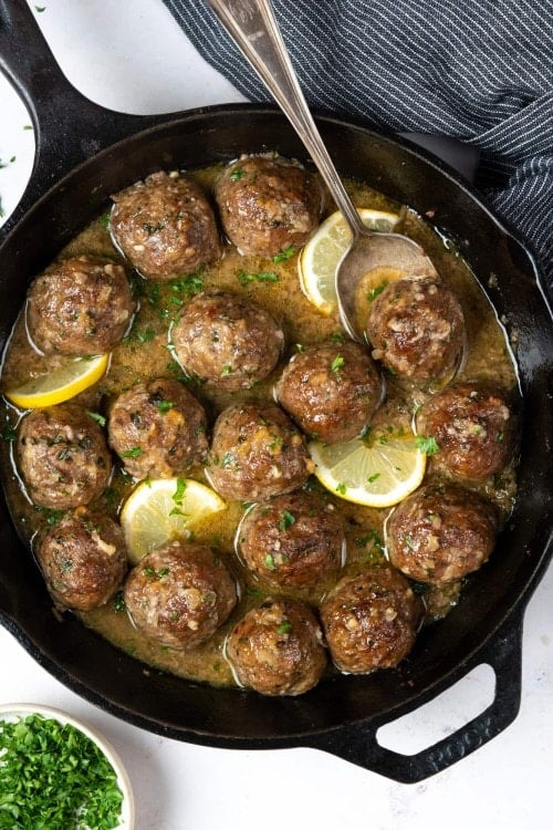 Baked meatballs in a butter garlic sauce on a skillet