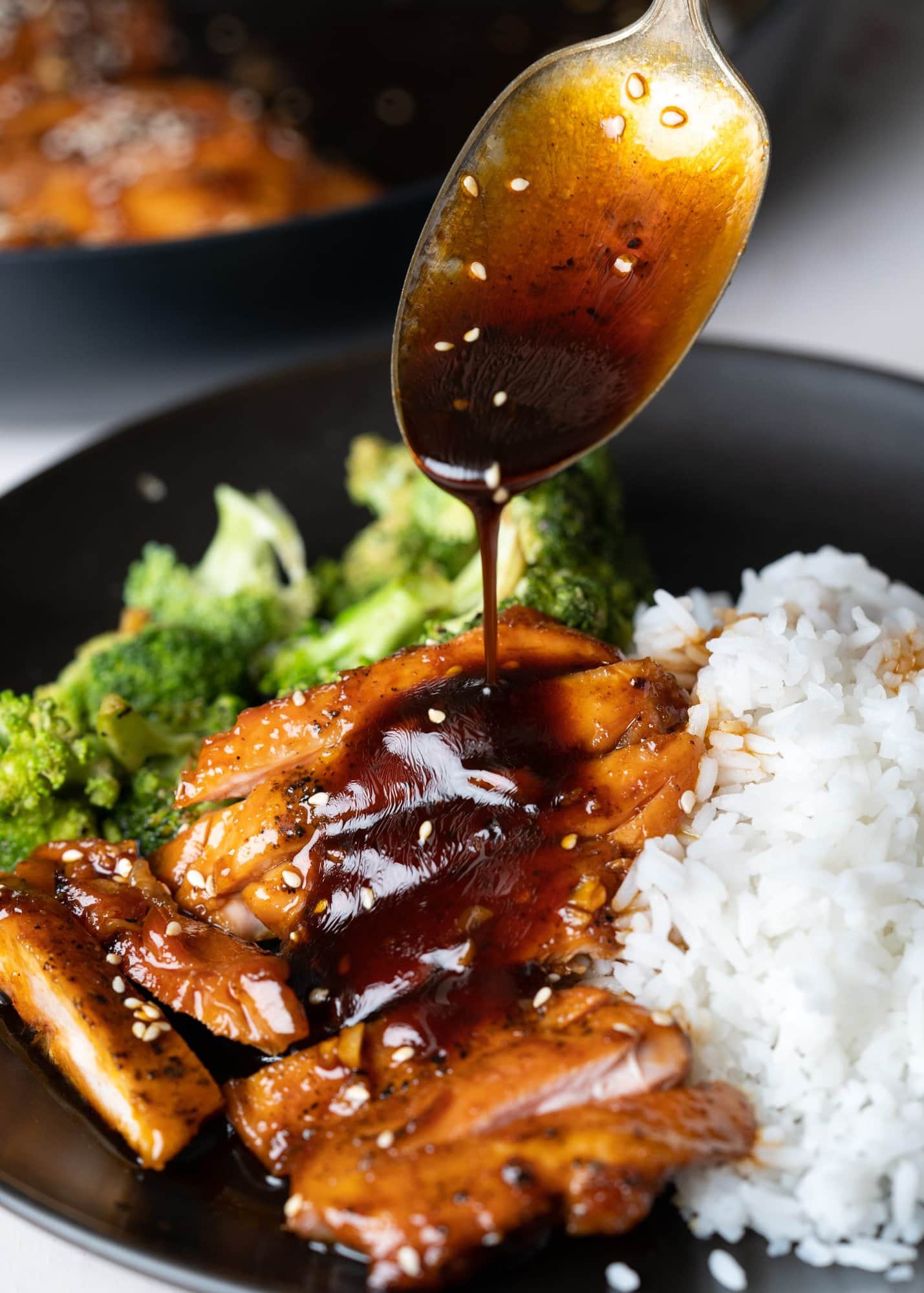 Sticky honey garlic sauce with a nice glaze is spooned over sliced chicken and served with rice and broccoli on a plate