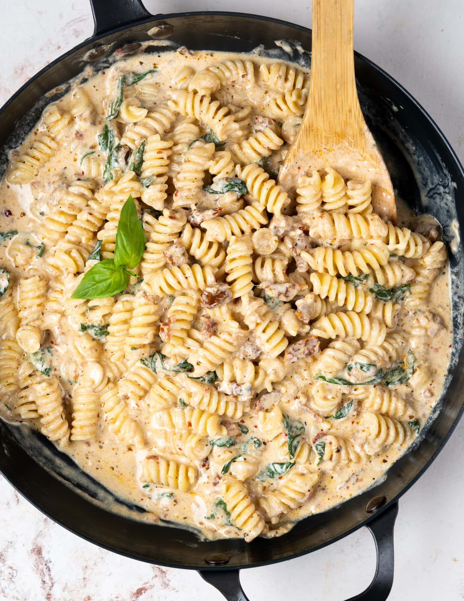 Top view of sun-dried tomato pasta made with pasta, cream, cheese and herbs in a skillet.