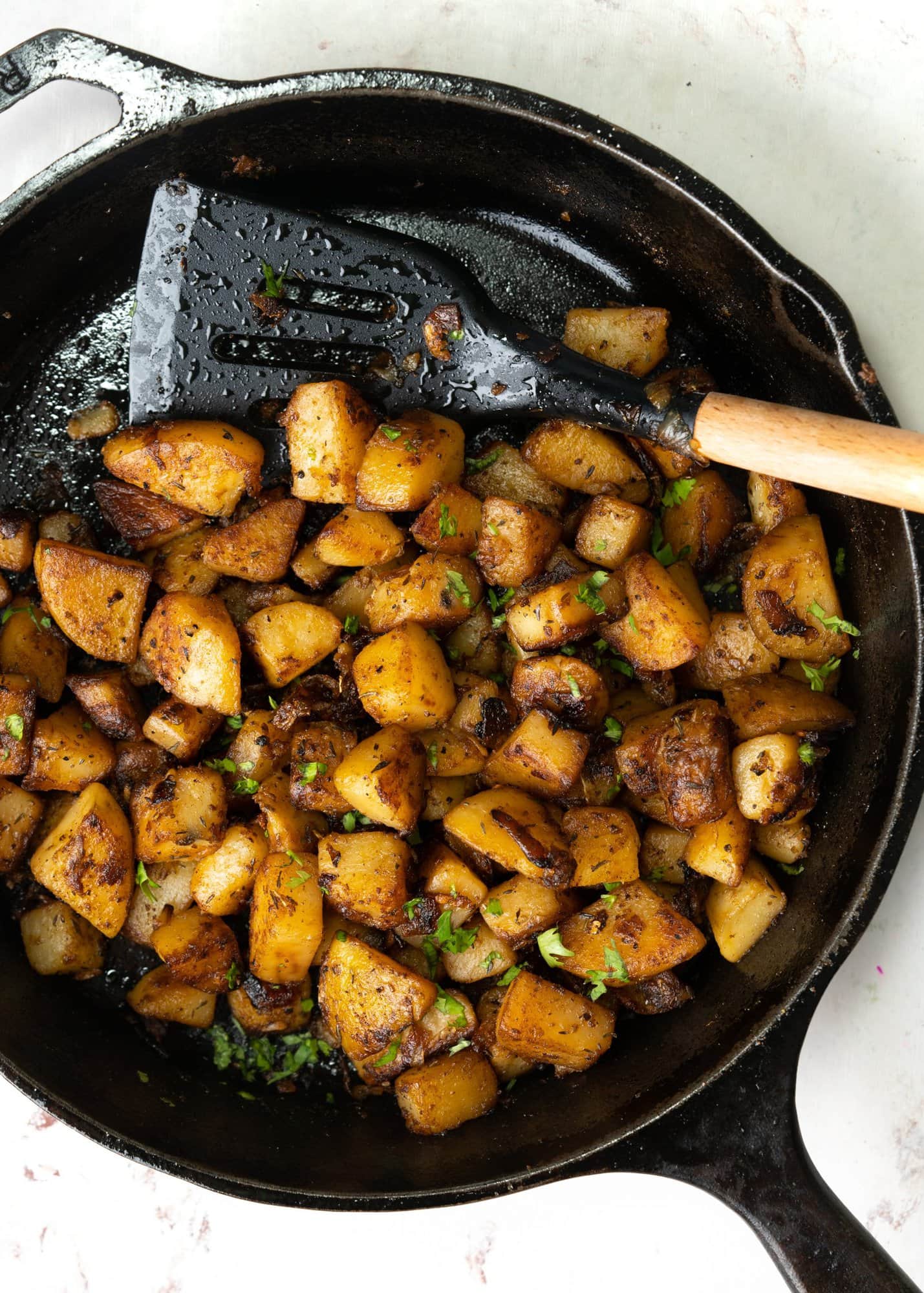 Crispy breakfast potatoes made in a skillet and shown with a spatula.
