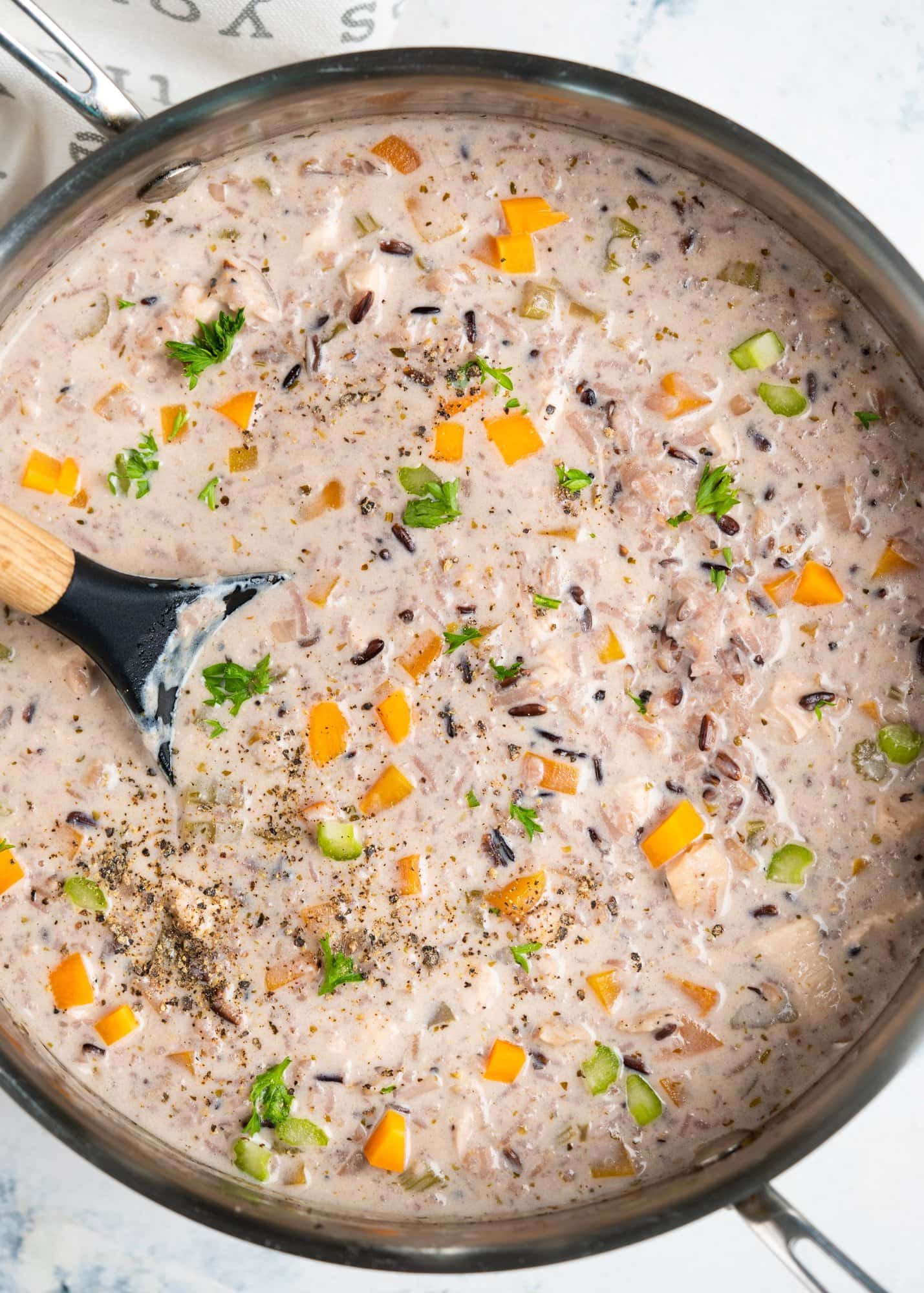 Top view showing creamy soup made with chicken and wild rice blend. Added veggies, mushrooms and chopped celery are shown in a soup pot.