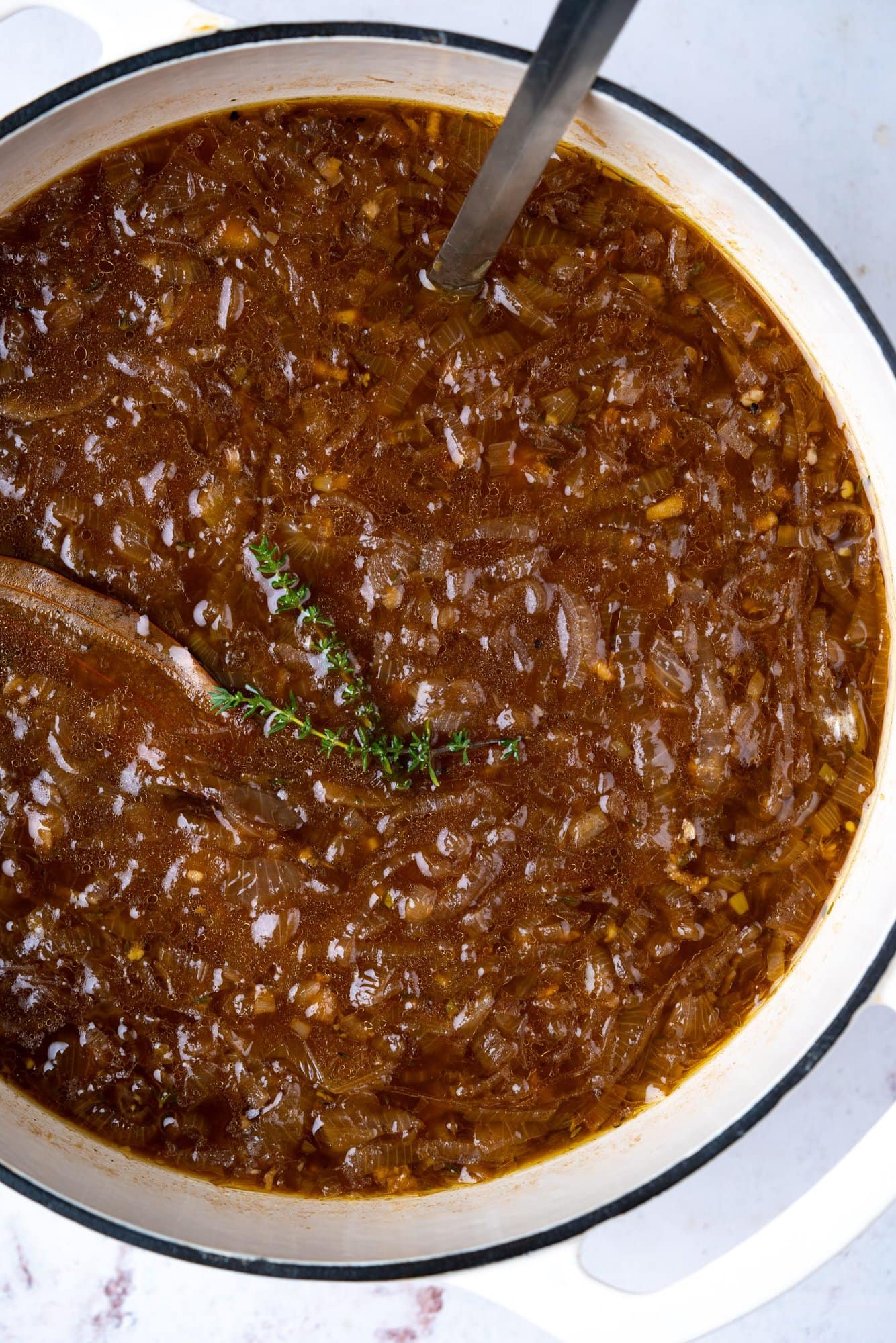 thyme on a bed of dark-brown color caramelized onions of french onion soup