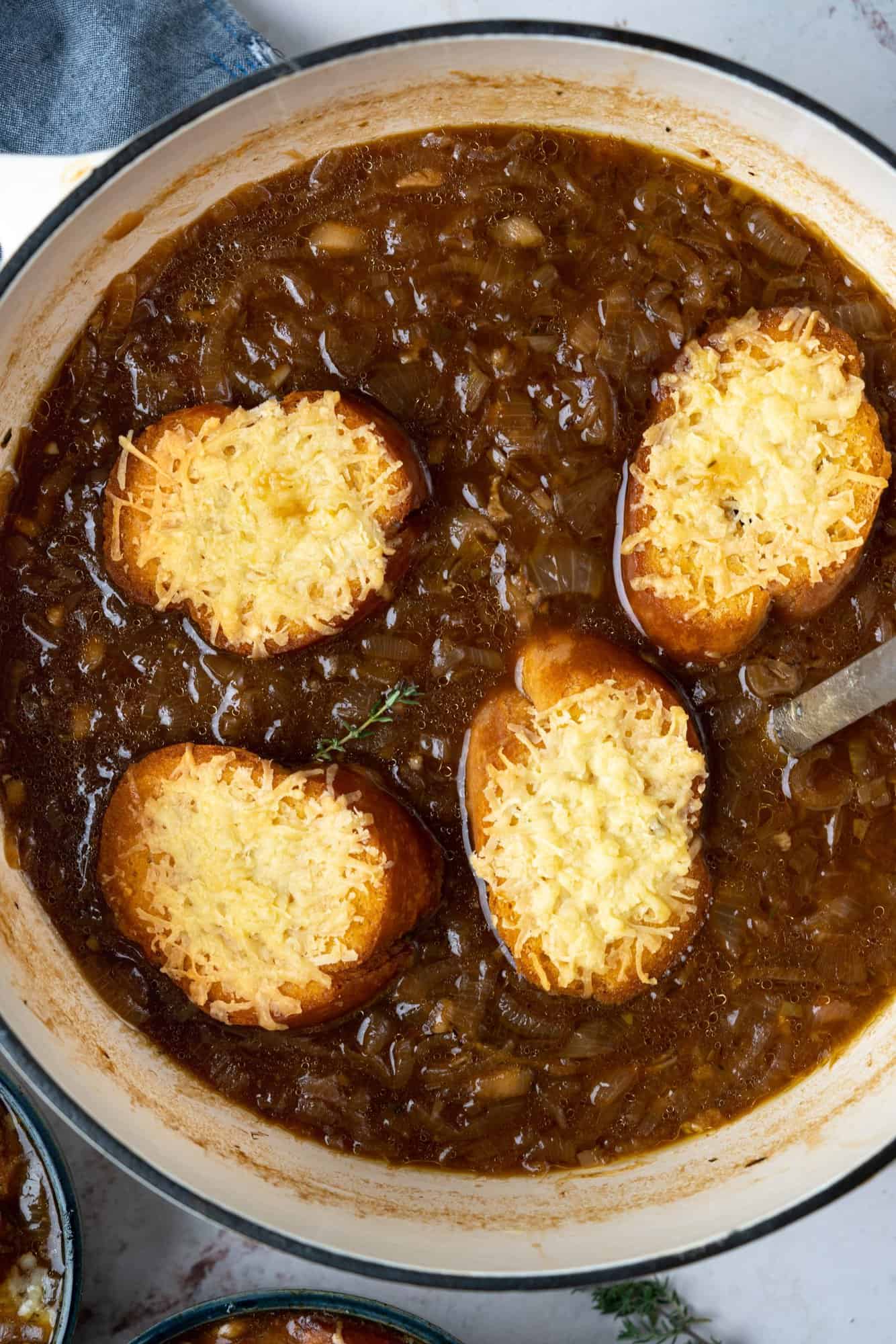 cheese topped toasted bread in a dutch oven of french onion