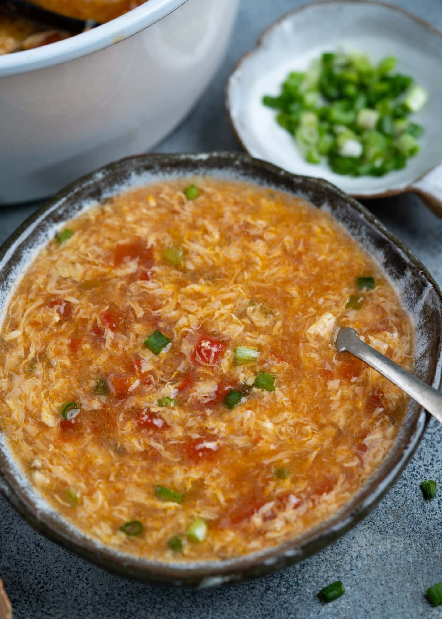 Bowl of Asian Tomato Egg Drop soup with green onion Garnish on top. 