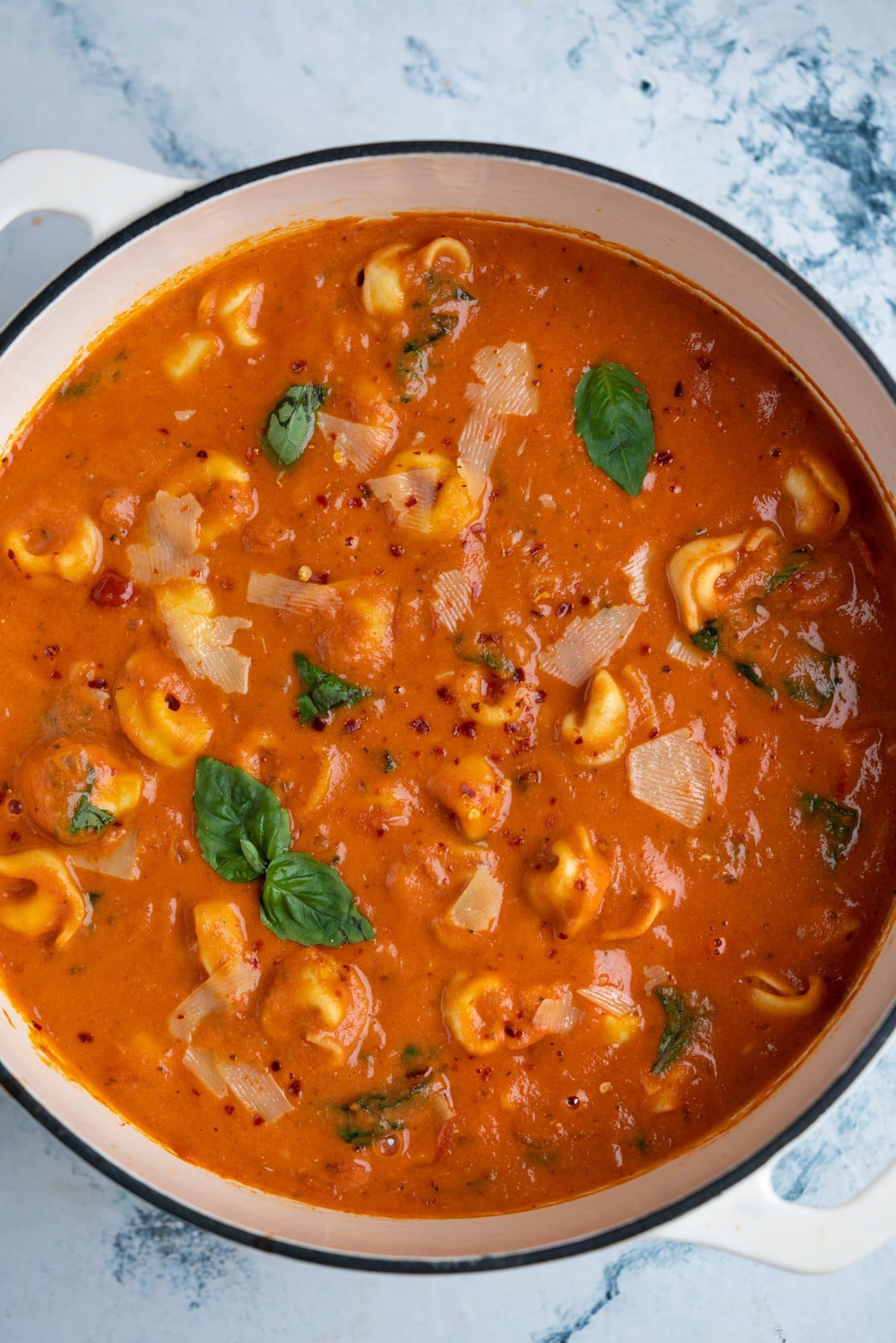 Fresh basil, parmesan cheese garnished on tomato tortellini soup which tastes creamy, cheesy and tangy.