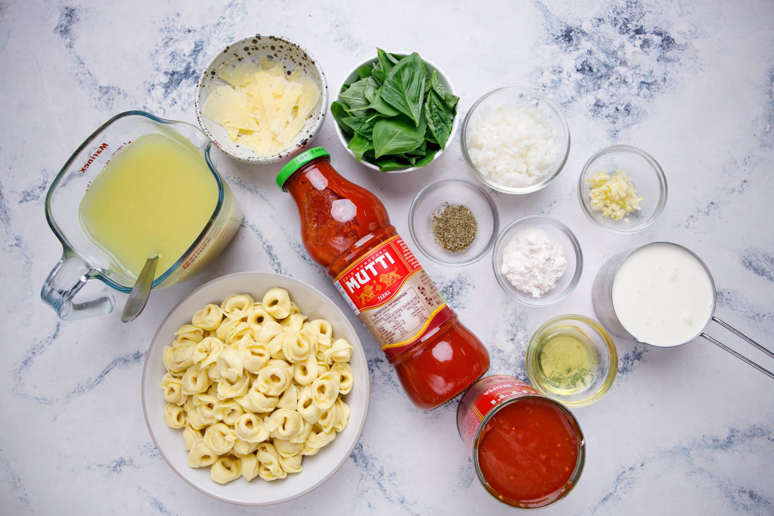 Ingreddients required for tomato tortellini soup - tortellini pasta, chicken stock, cheese, tomato diced and puree, basil, olive oil