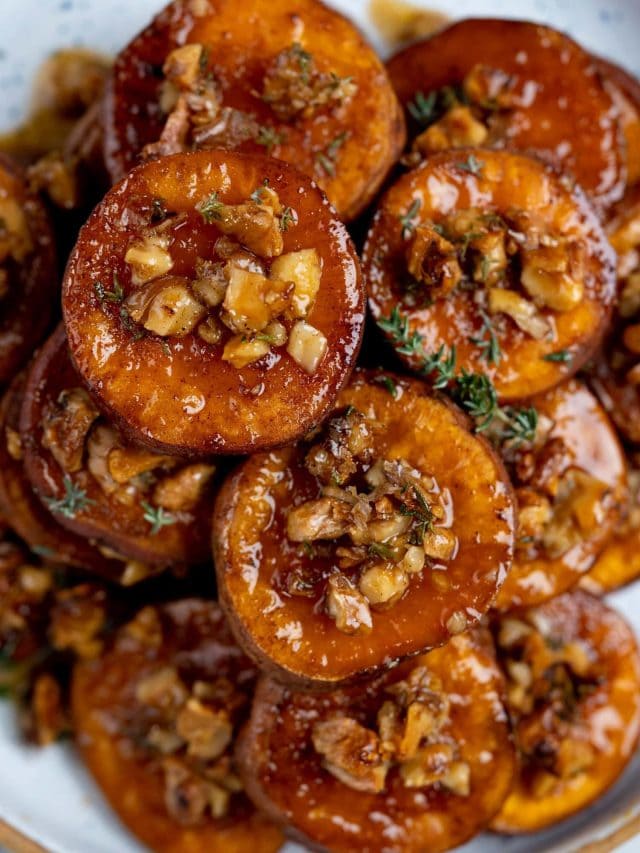 Roasted sweet potatoes in a heap with a glaze of maple syrup and crunchy walnuts on top.