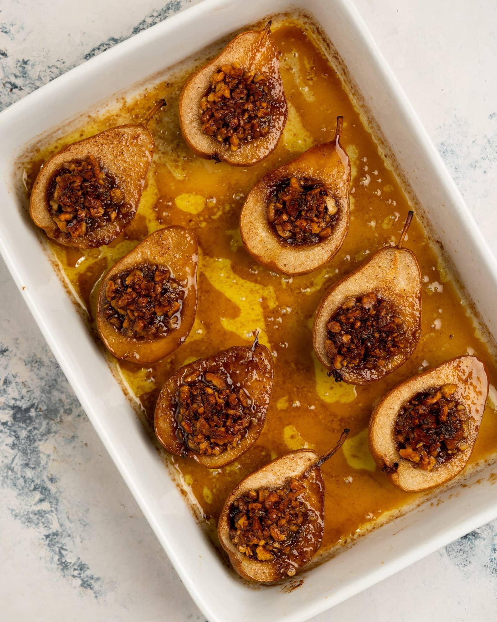 Pears baked with crunch walnut mix in its core with a caramelized sauce in the tray.