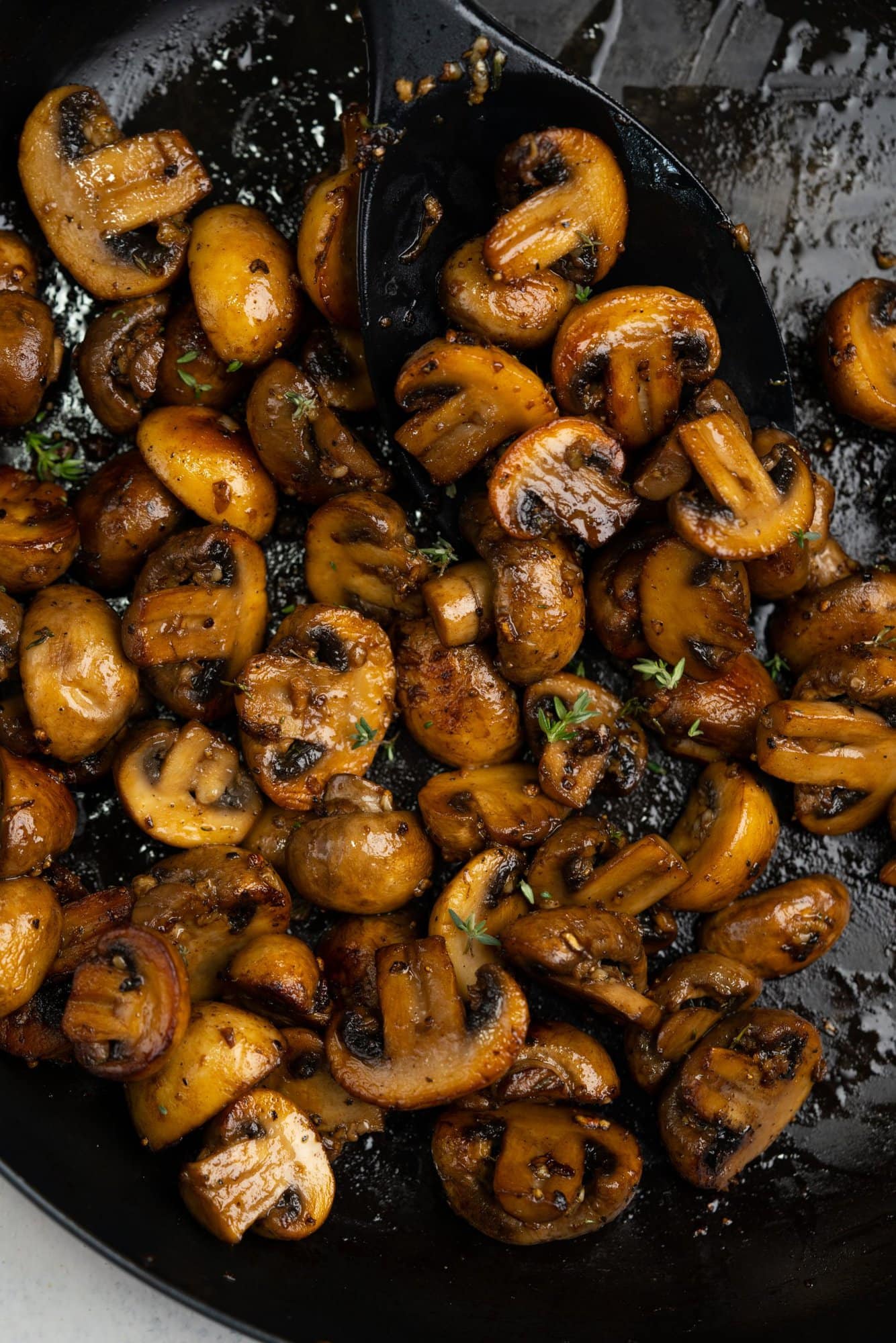 Laddle full of of butter and garlic glazed mushrooms in a skillet