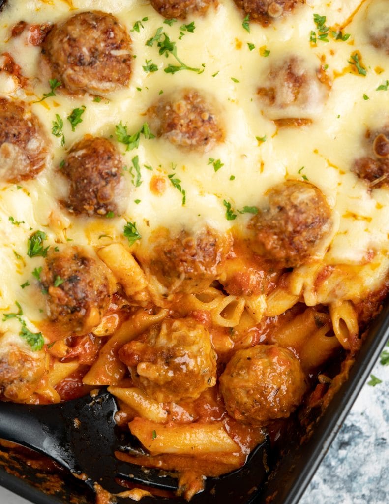 Corner of meatball casserole sliced to shown saucy pasta, tender meatballs and gooey cheese