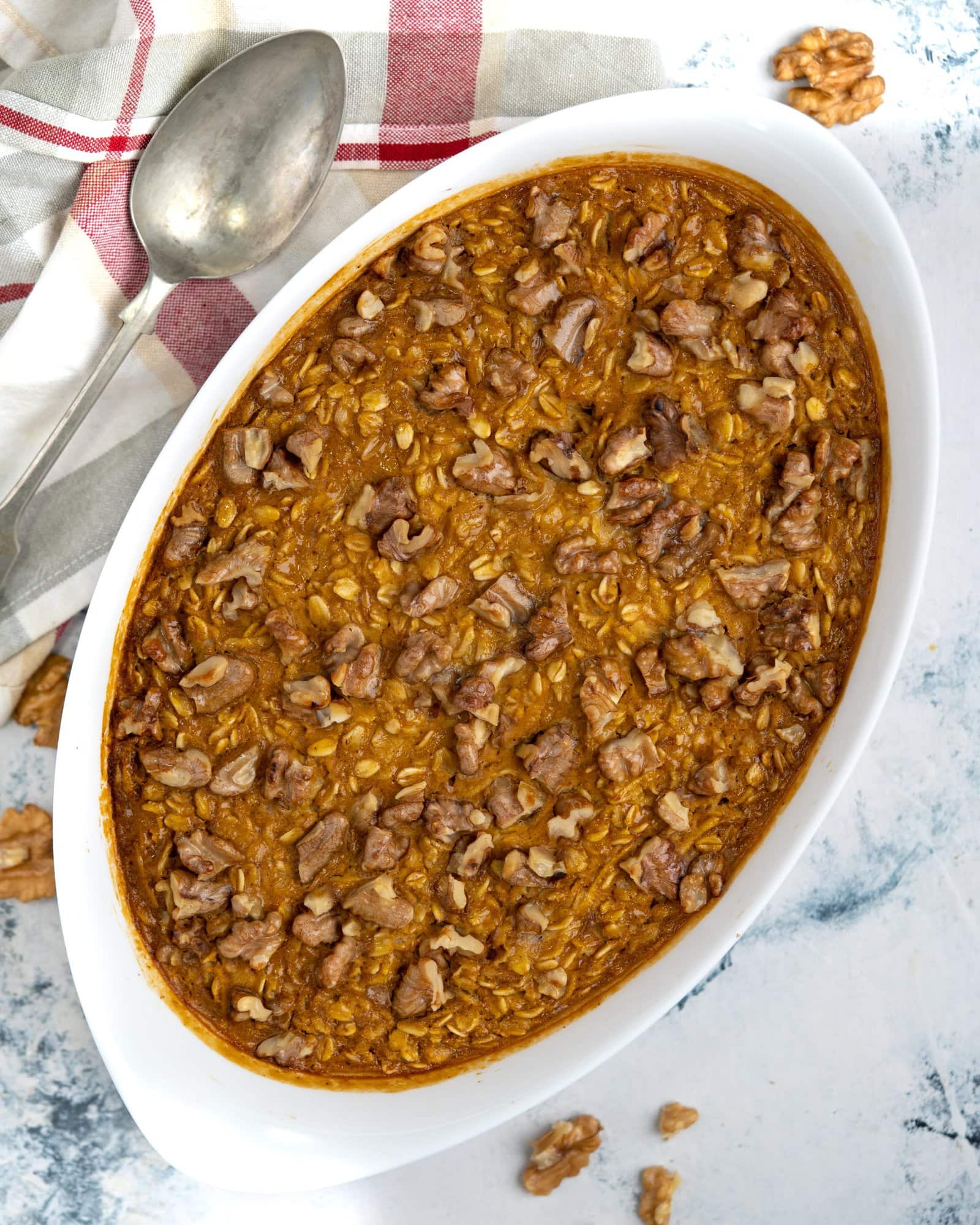 Top view of Baked pumpkin oatmeal in a casserole topped with walnut chunks.