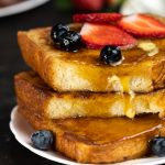 maple syrup dripping on the sides of a stack of brioche french toasts.