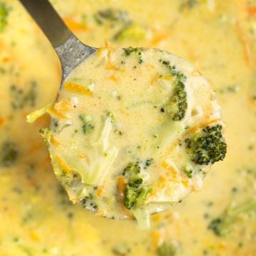 Ladle showing broccoli, sliced carrots in a cheesy soup made with cheddar.
