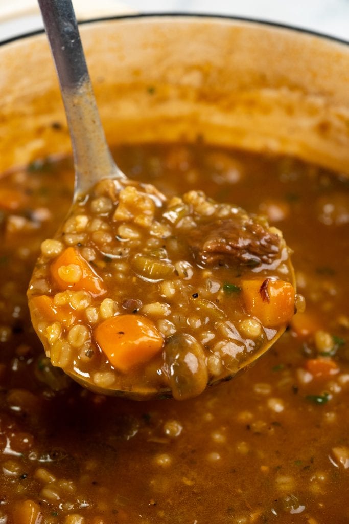 Ladle showing barley soup with roasted chuck