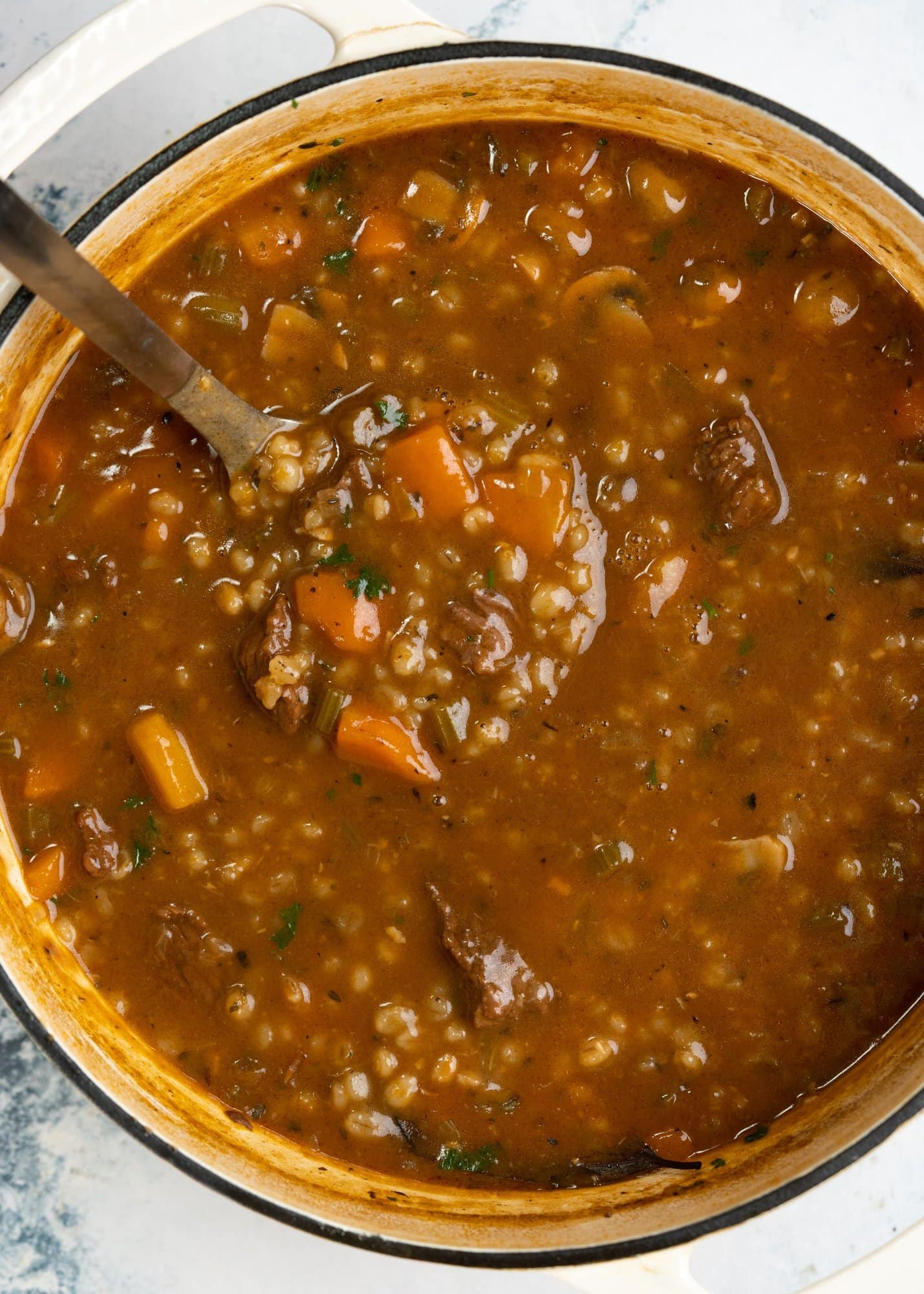 Barley soup made in a dutch oven with beef and vegetables in a broth.