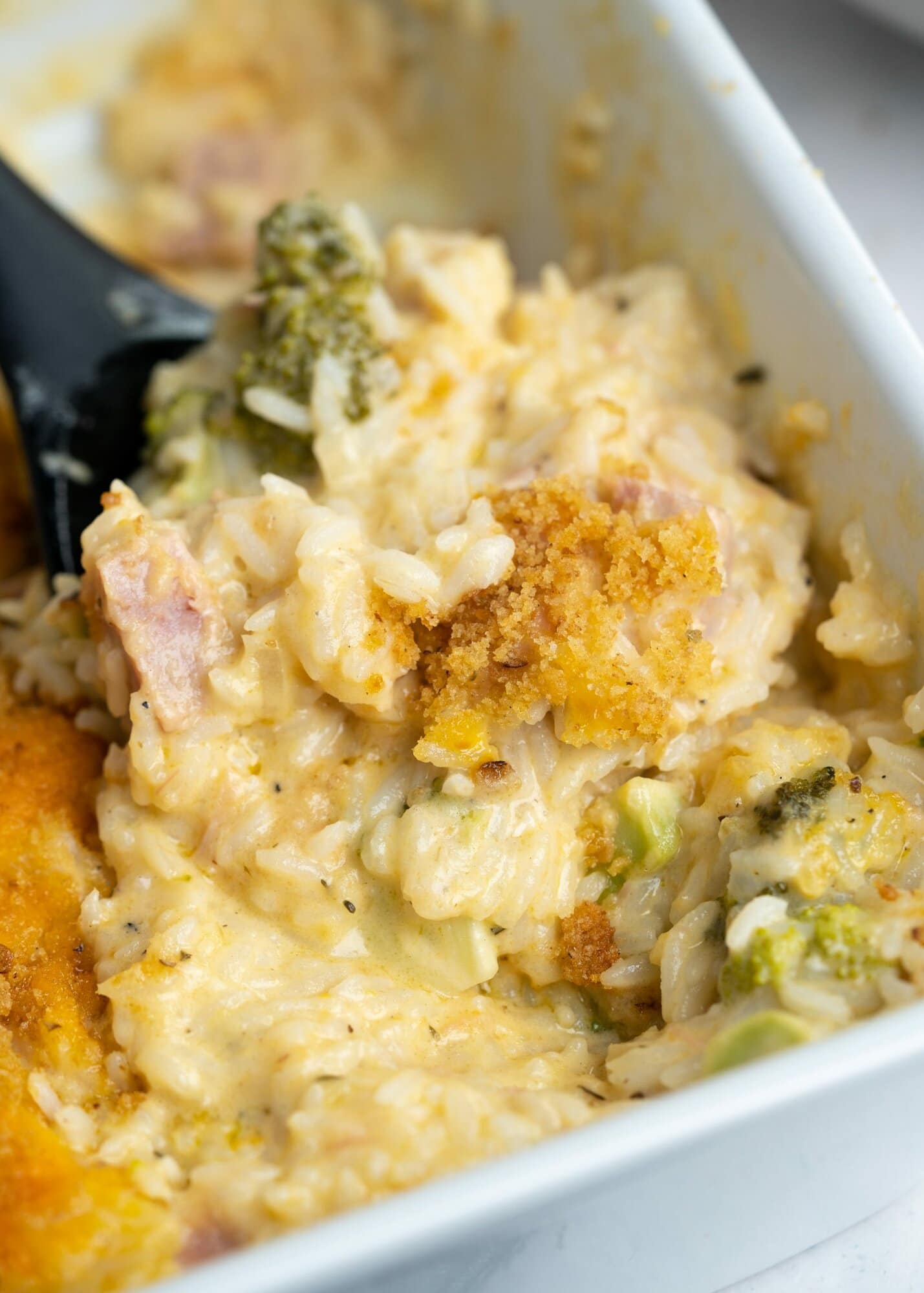 Close up view of leftover ham casserole having rice, ham, broccoli with a creamy and cheesy sauce along with crusty top.