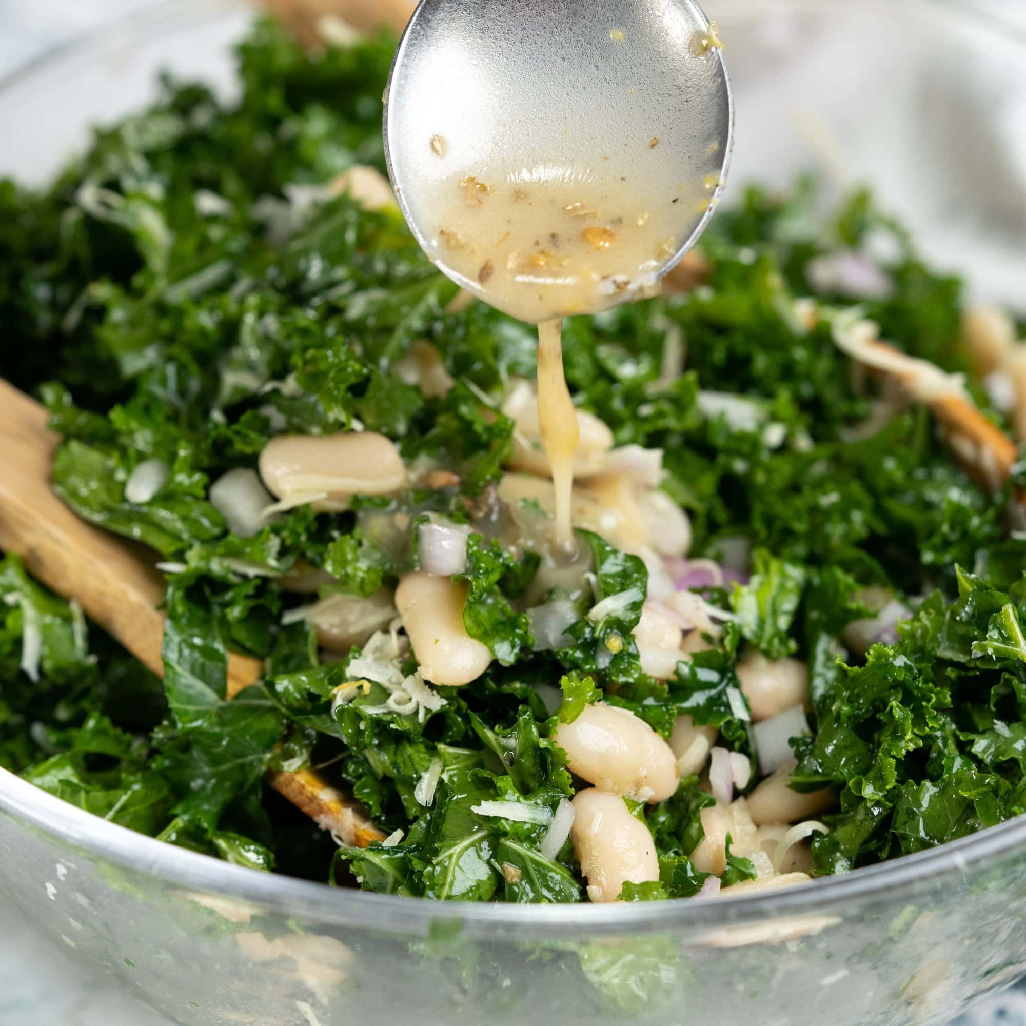 Lemon vinaigrette drizzled on top of white bean salad with kale and onions.